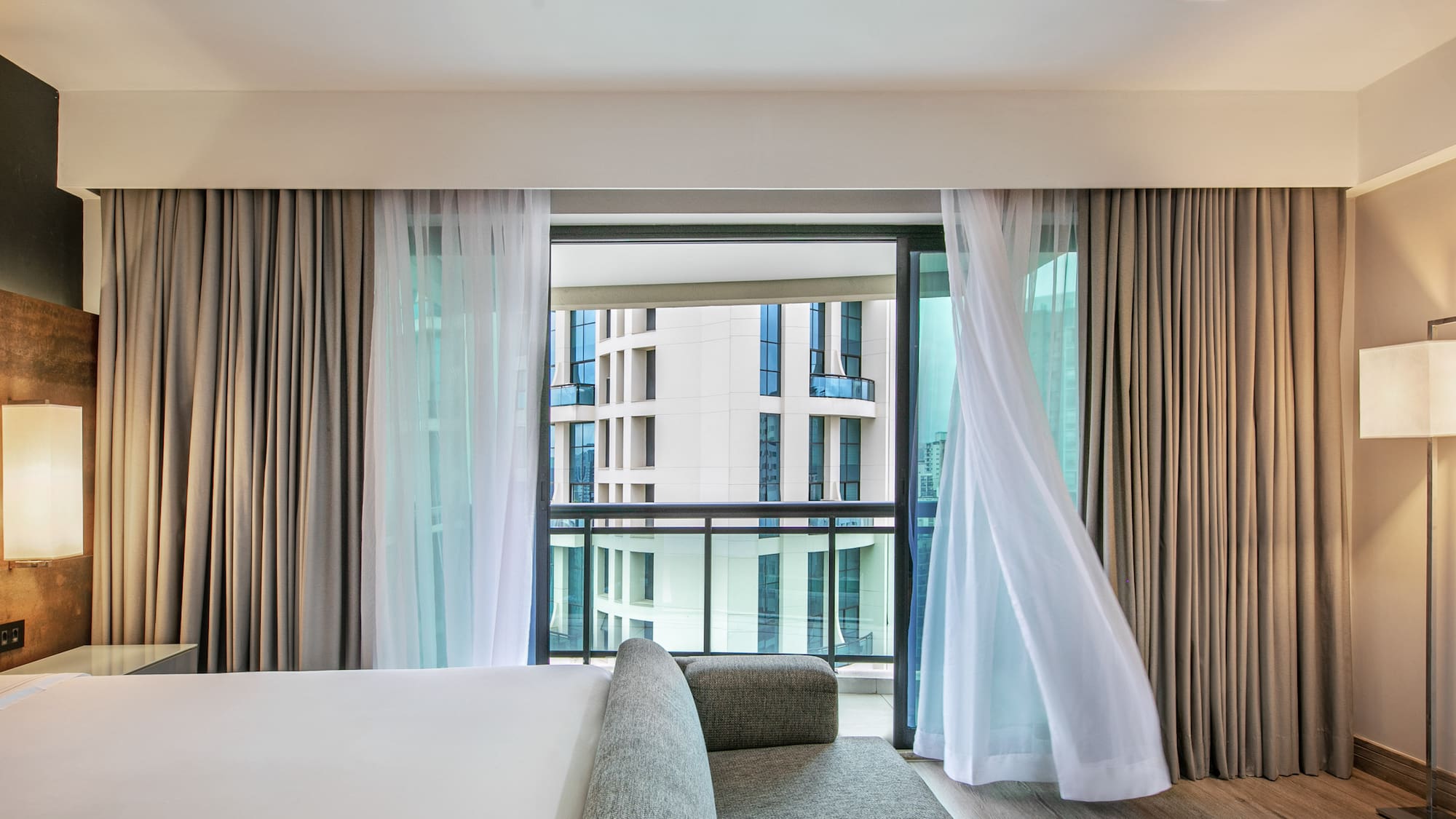 Quarto de hotel moderno com cortinas ao vento e vista para prédios. - Deluxe Queen Room com Varanda - Meliá Ibirapuera, São Paulo