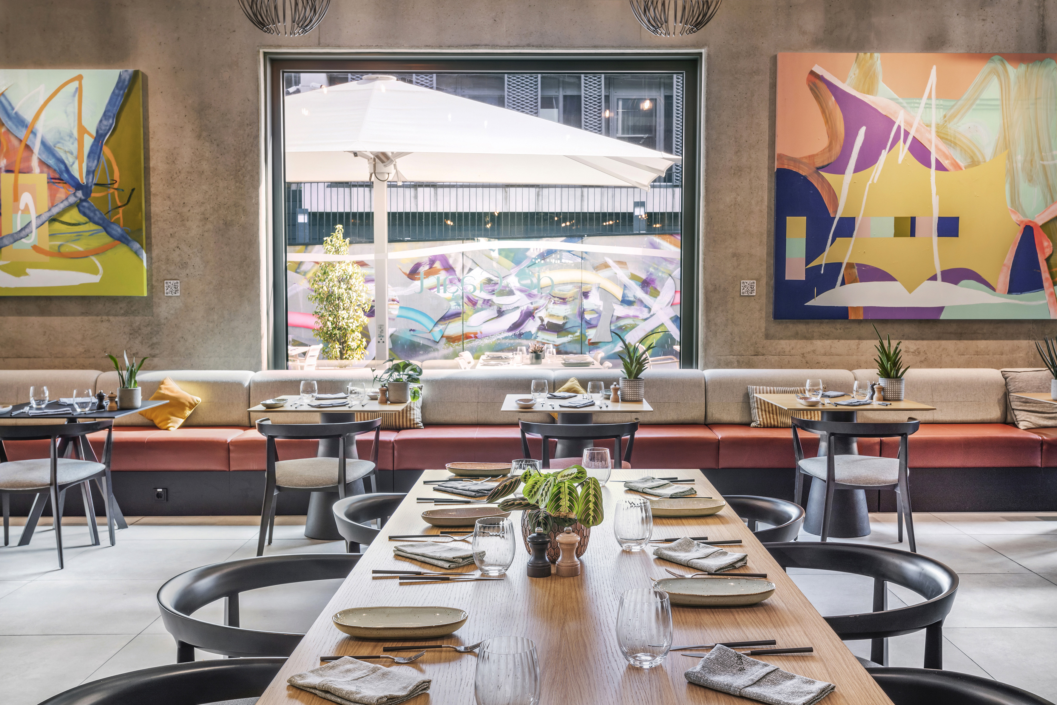 Modern restaurant interior with communal dining table, booth seating, and abstract wall art. - De Gaart, Cuisine locale - INNSiDE Luxembourg, Luxembourg
