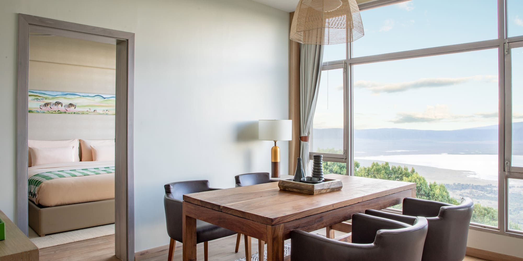 Modern dining area with lake view through large windows, adjoining bedroom.