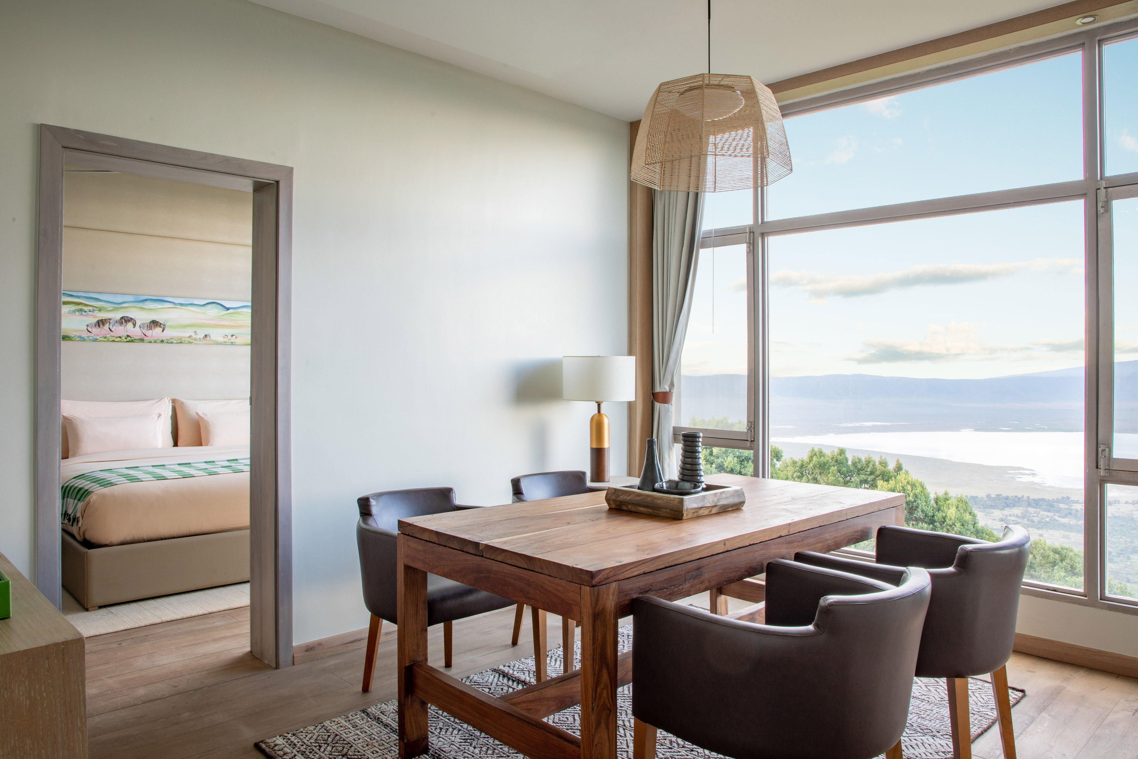 Modern dining area with lake view through large windows, adjoining bedroom.