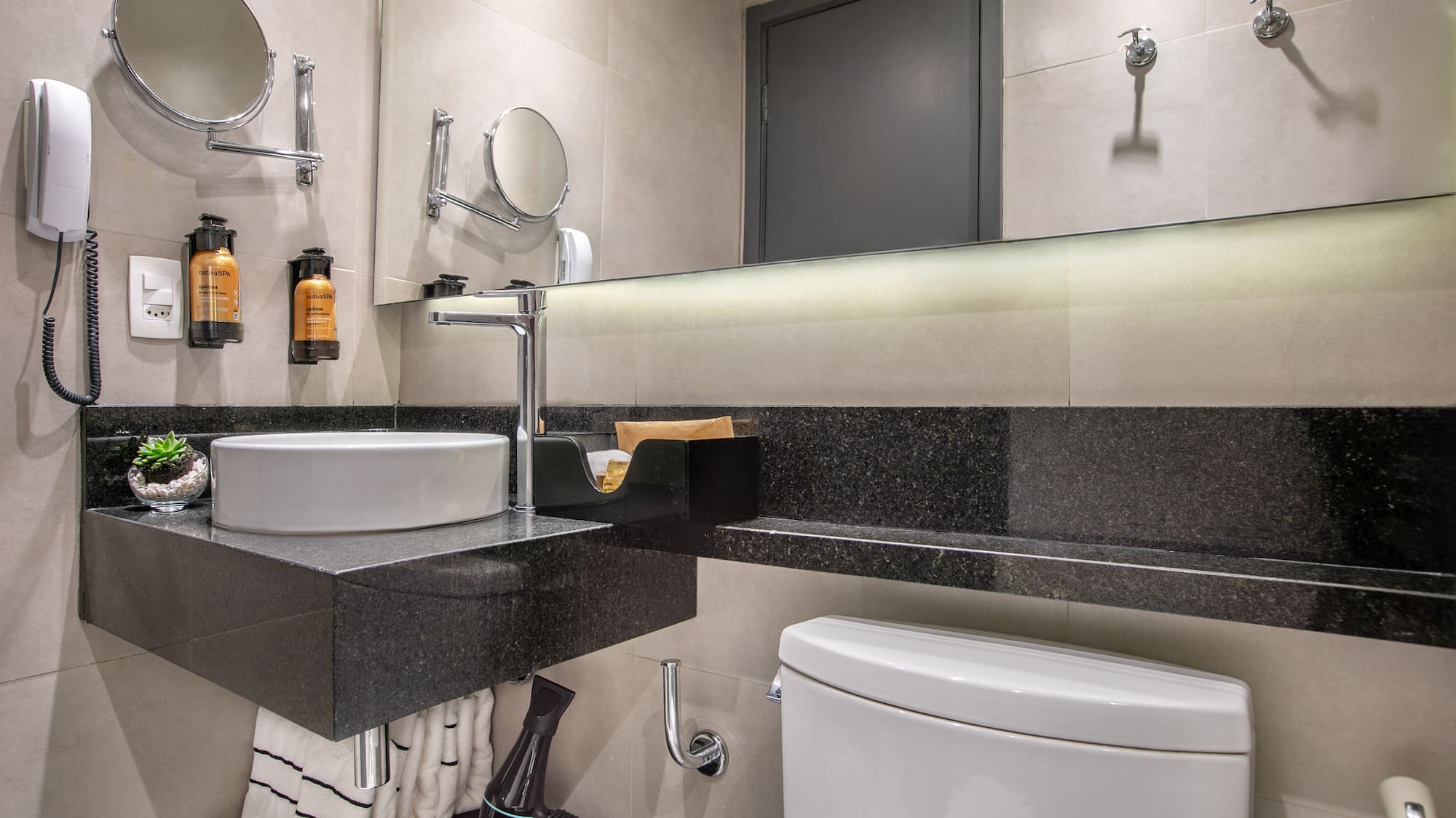 Modern hotel bathroom with vessel sink, black granite countertop, and vanity mirror. - Deluxe Queen Room com Varanda - Meliá Ibirapuera, São Paulo