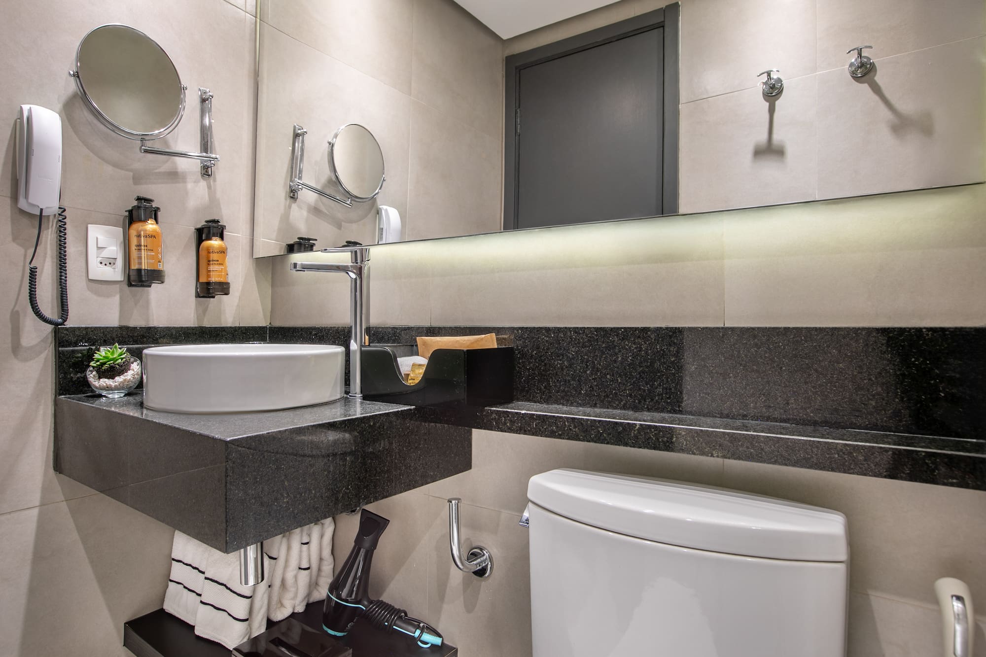 Modern hotel bathroom with vessel sink, black granite countertop, and vanity mirror. - Deluxe Queen Room com Varanda - Meliá Ibirapuera, São Paulo