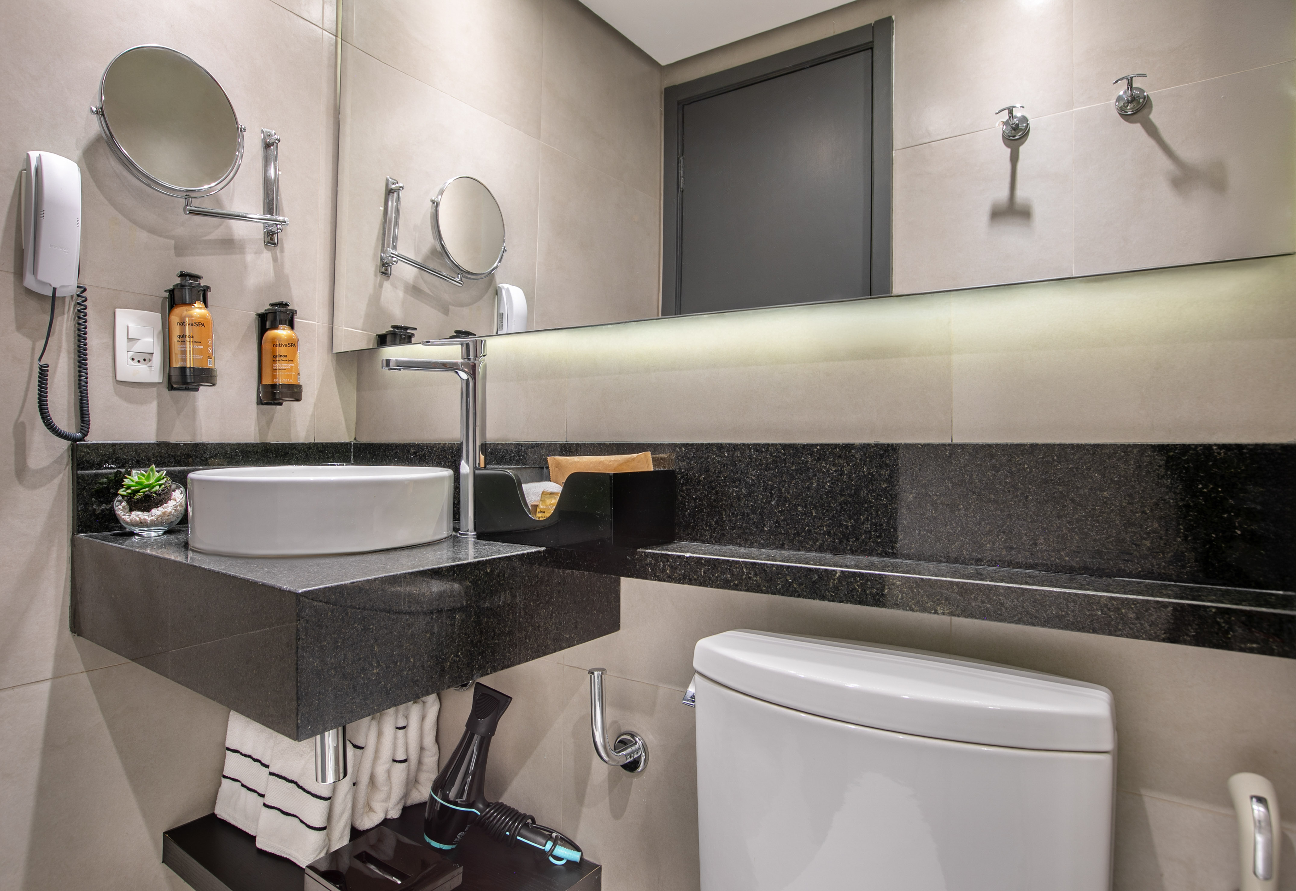 Modern hotel bathroom with vessel sink, black granite countertop, and vanity mirror. - Deluxe Queen Room com Varanda - Meliá Ibirapuera, São Paulo