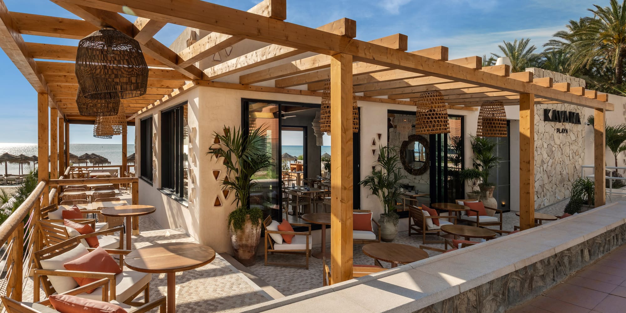 Kayana Playa beach restaurant with wooden pergola, outdoor dining, and ocean view.