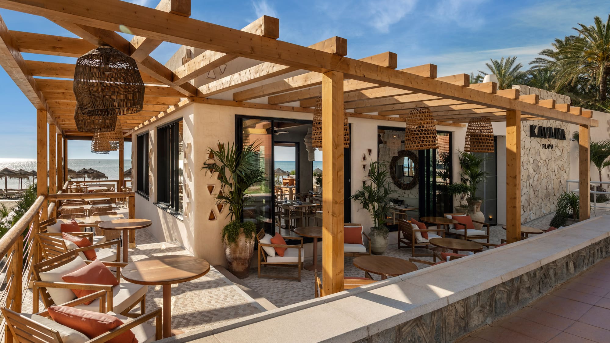 Kayana Playa beach restaurant with wooden pergola, outdoor dining, and ocean view.