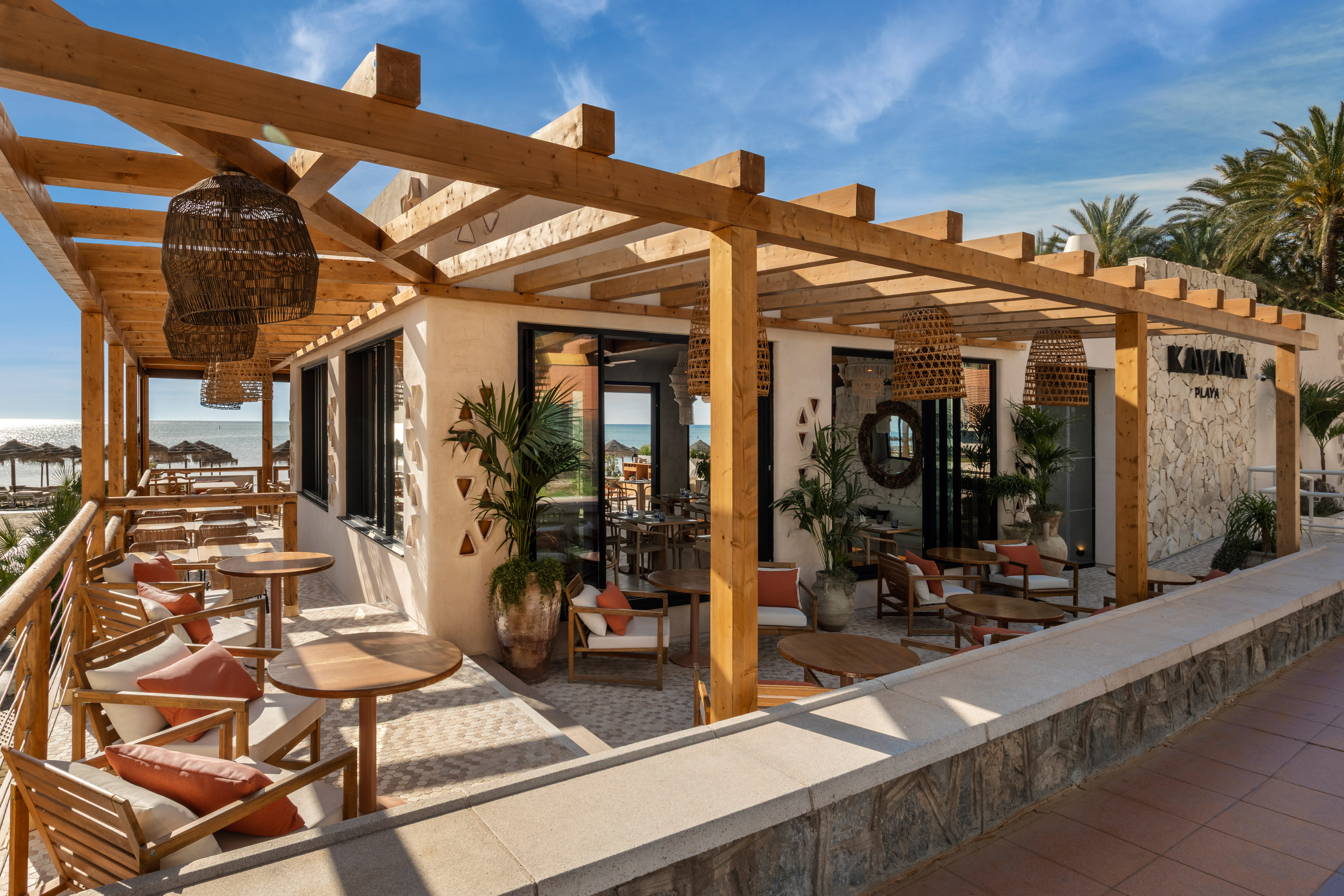 Kayana Playa beach restaurant with wooden pergola, outdoor dining, and ocean view.
