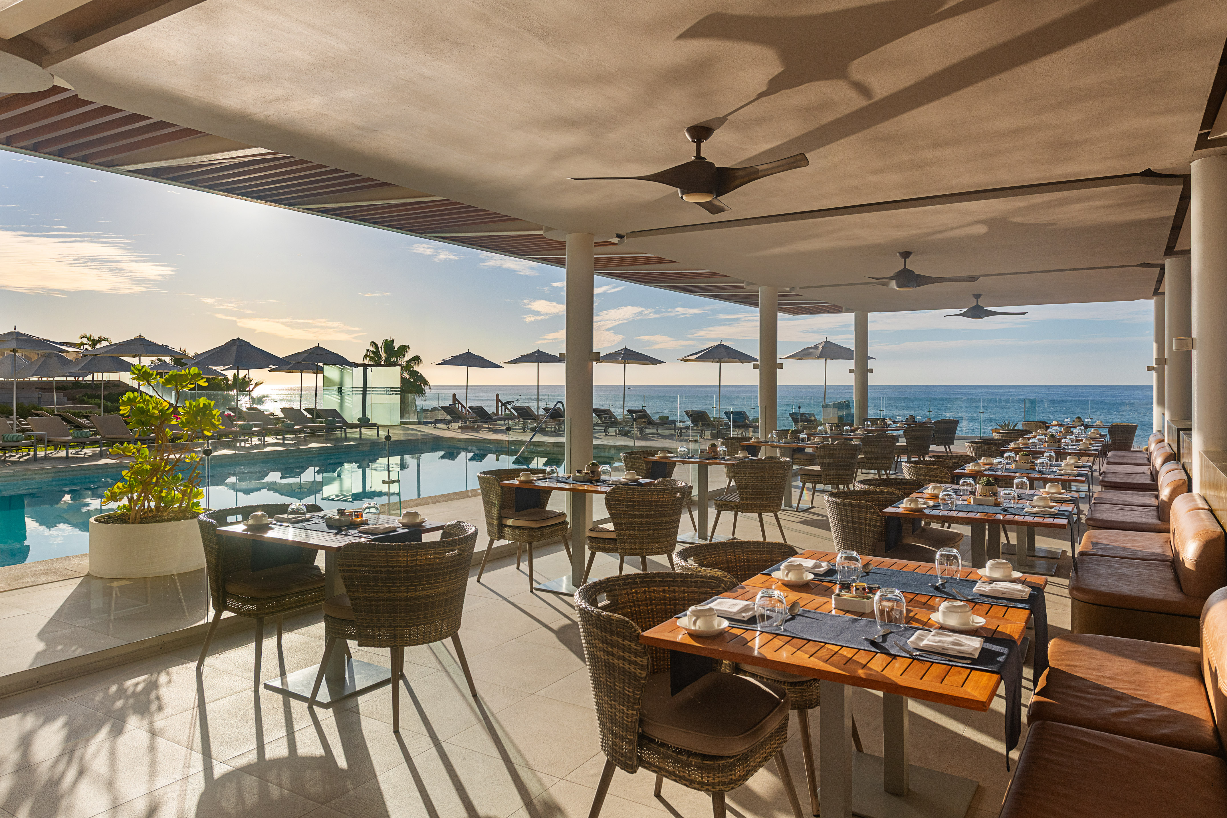 Oceanfront outdoor resort restaurant with poolside dining tables.