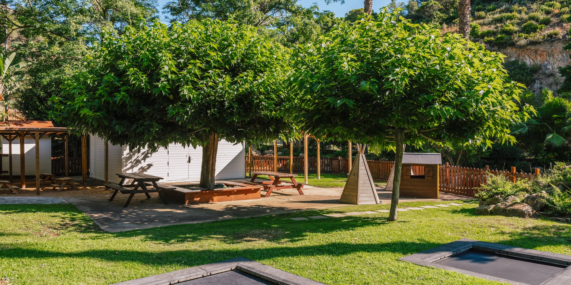 a playground with trees and a small trampoline