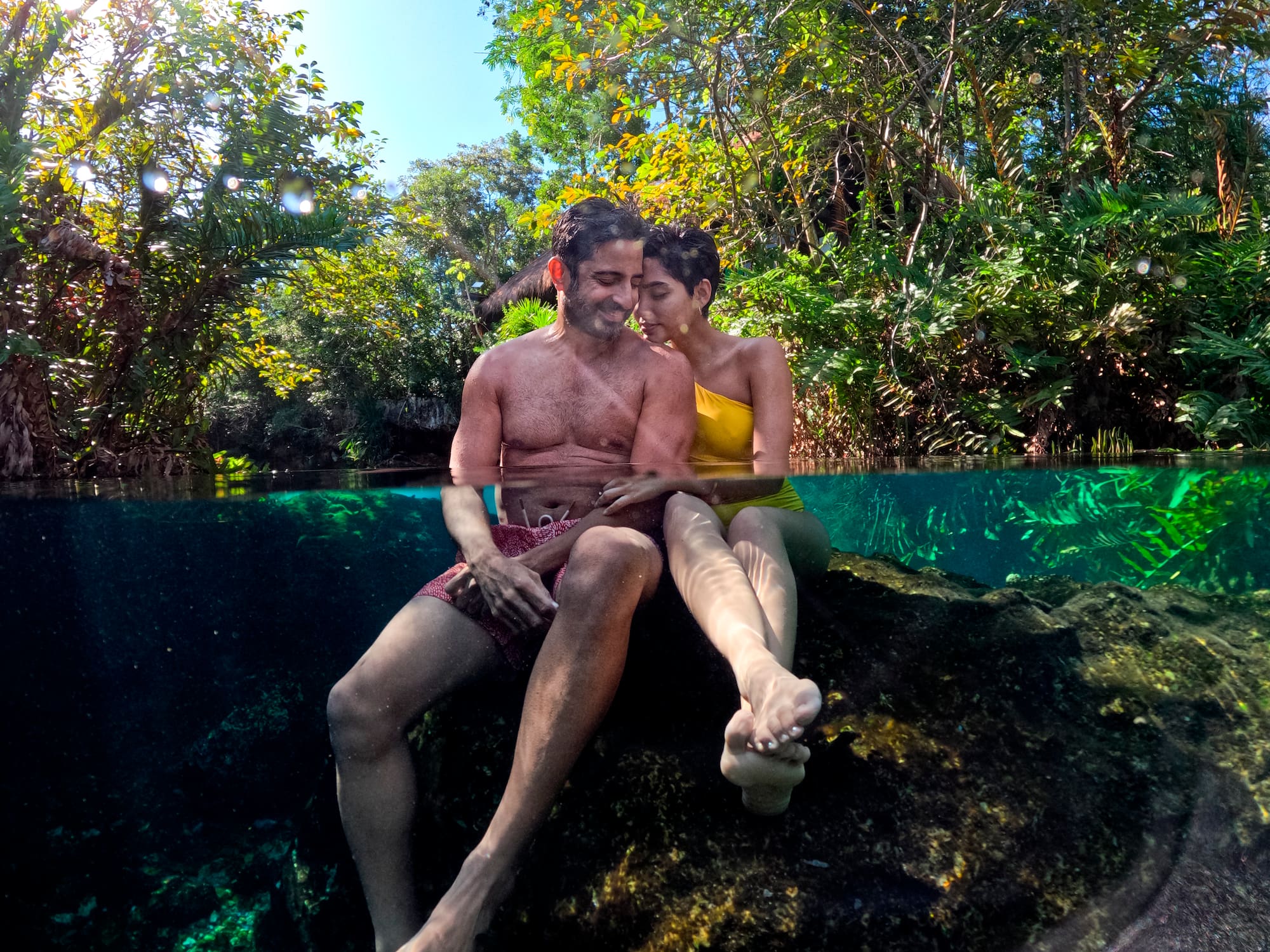 a man and woman sitting on a rock in water