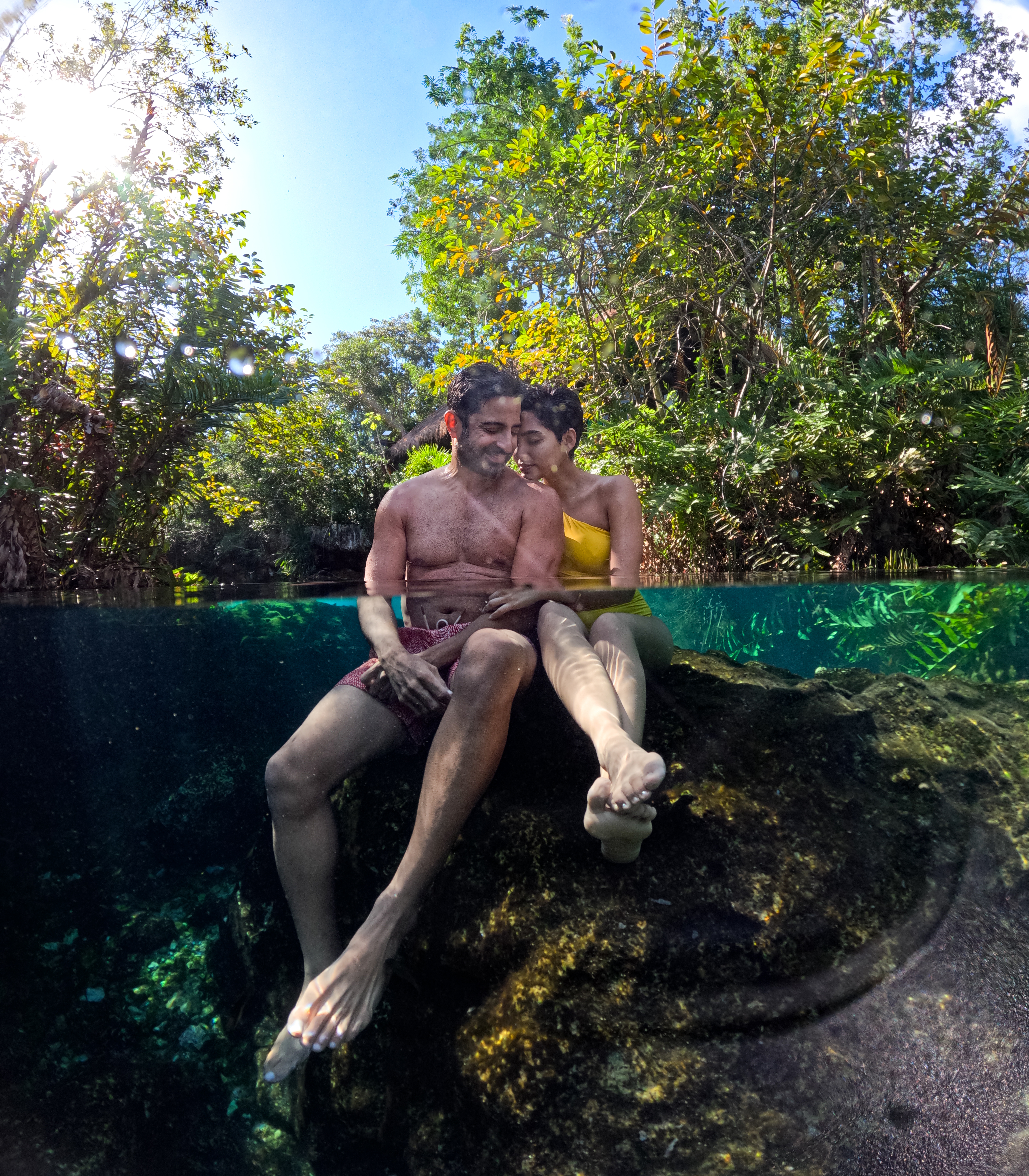 a man and woman sitting on a rock in water
