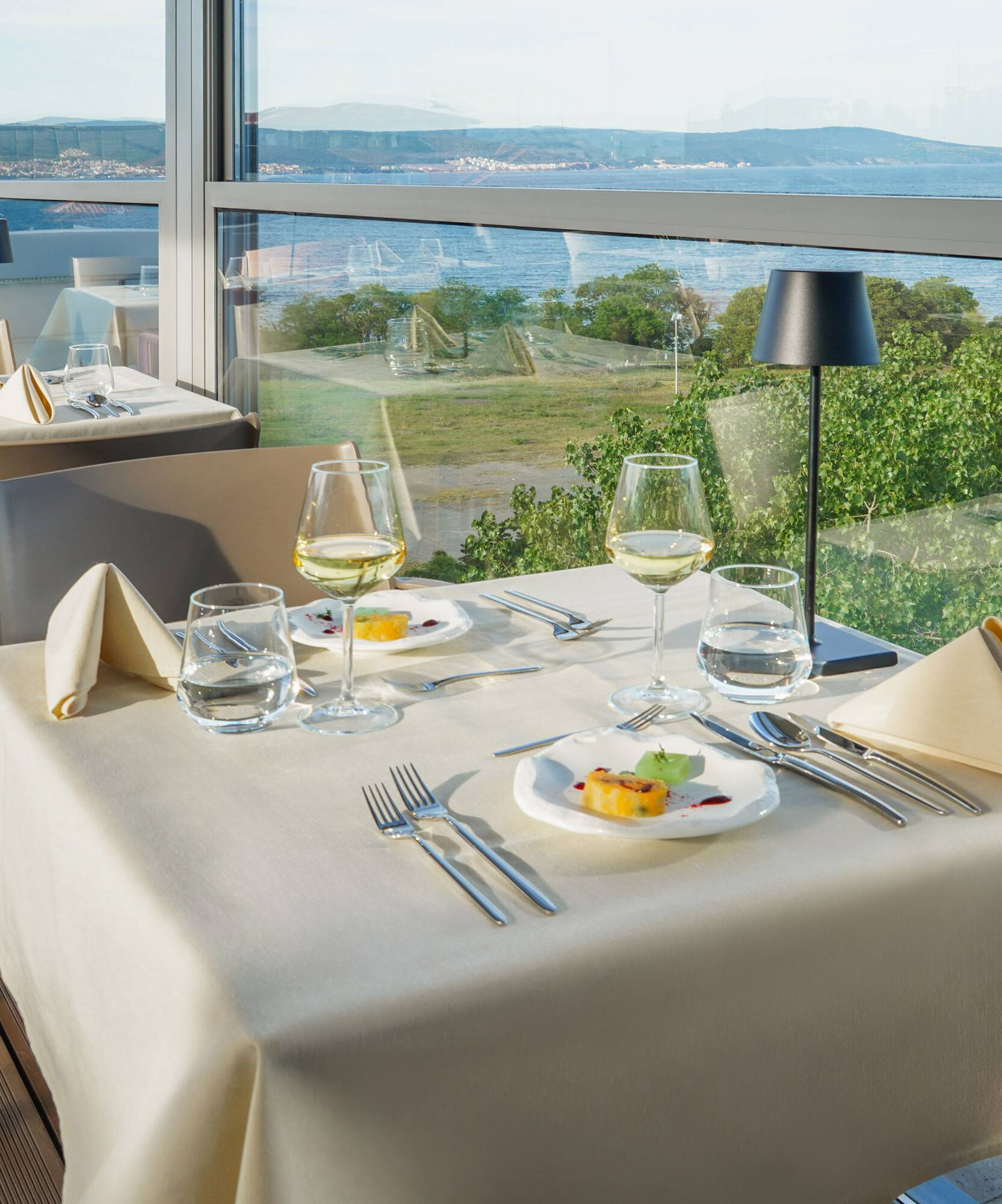 a table with plates and glasses on it and a view of the ocean