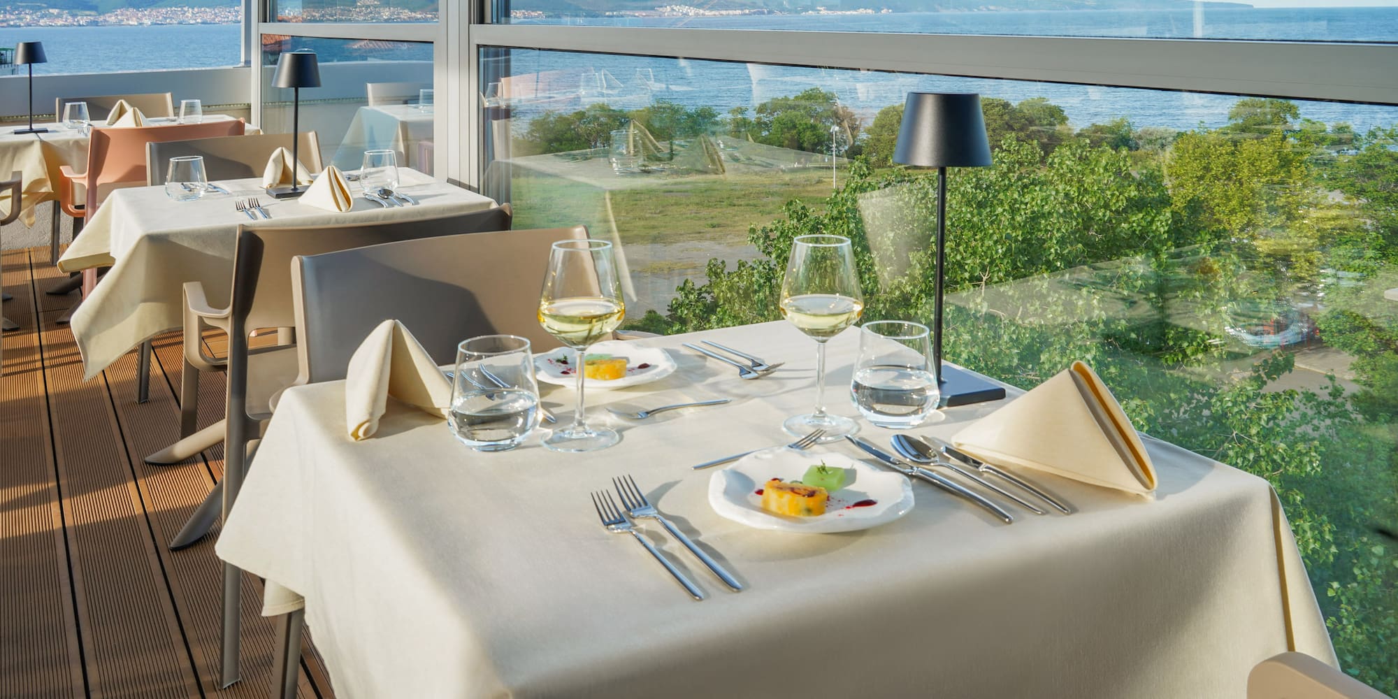 a table with plates and glasses on it and a view of the ocean