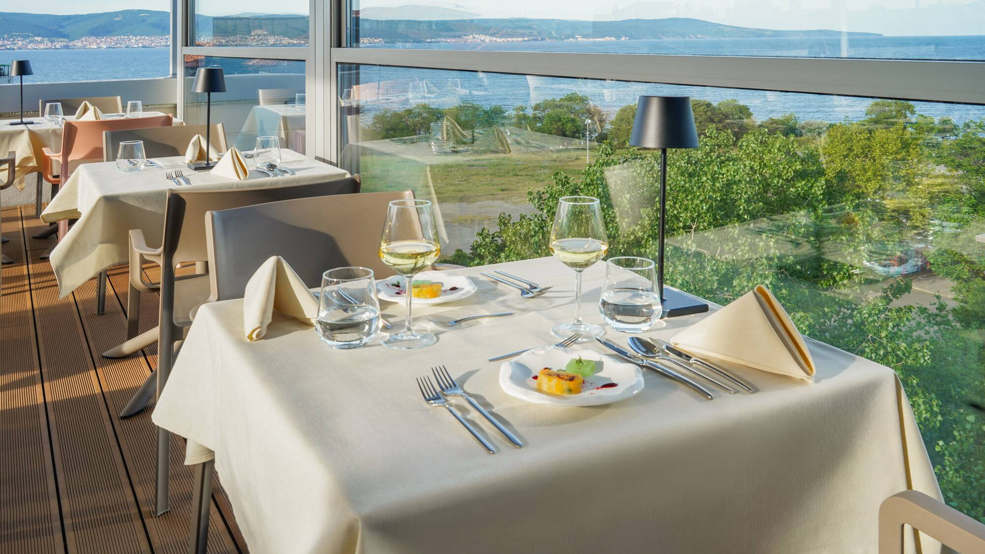 a table with plates and glasses on it and a view of the ocean