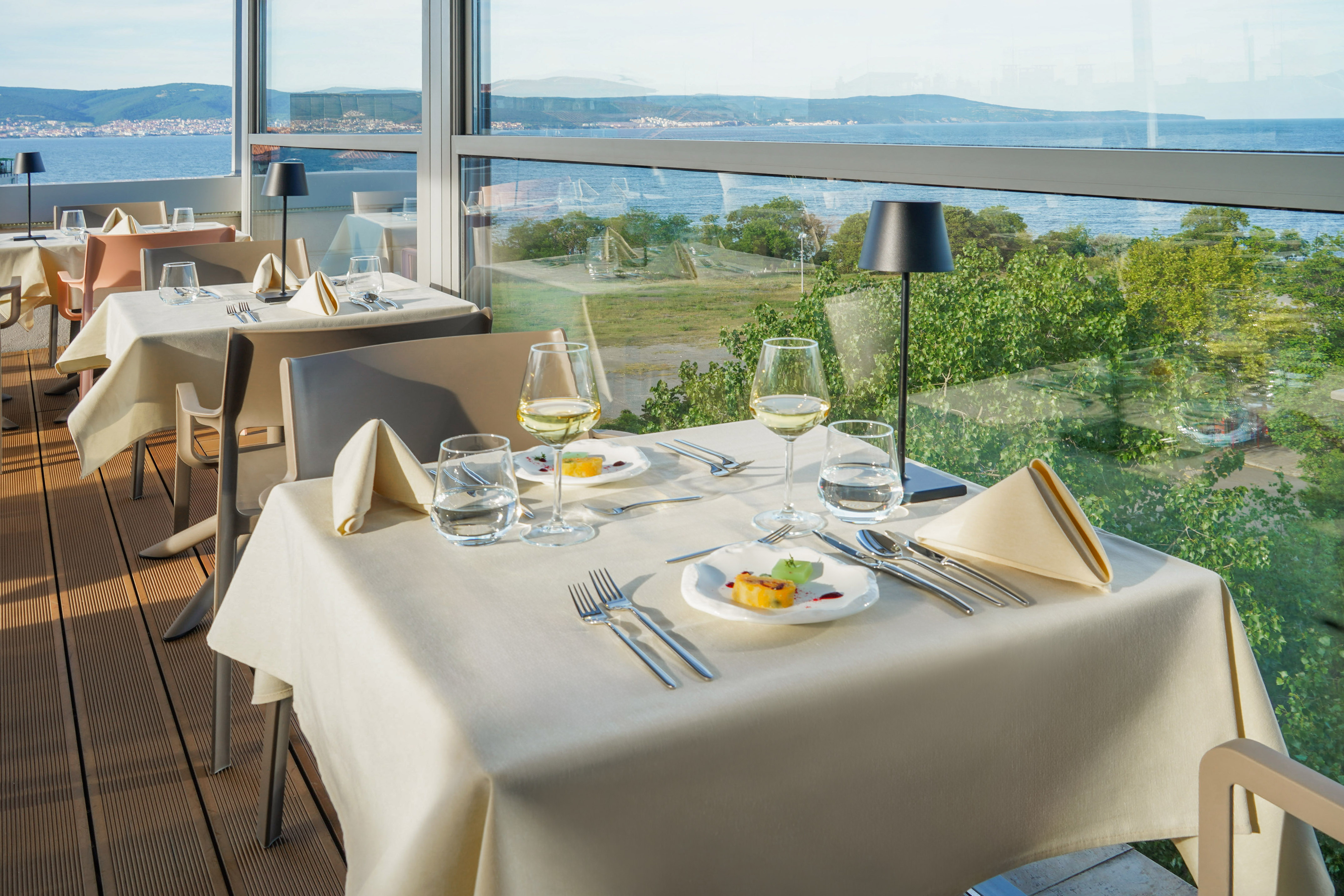 a table with plates and glasses on it and a view of the ocean