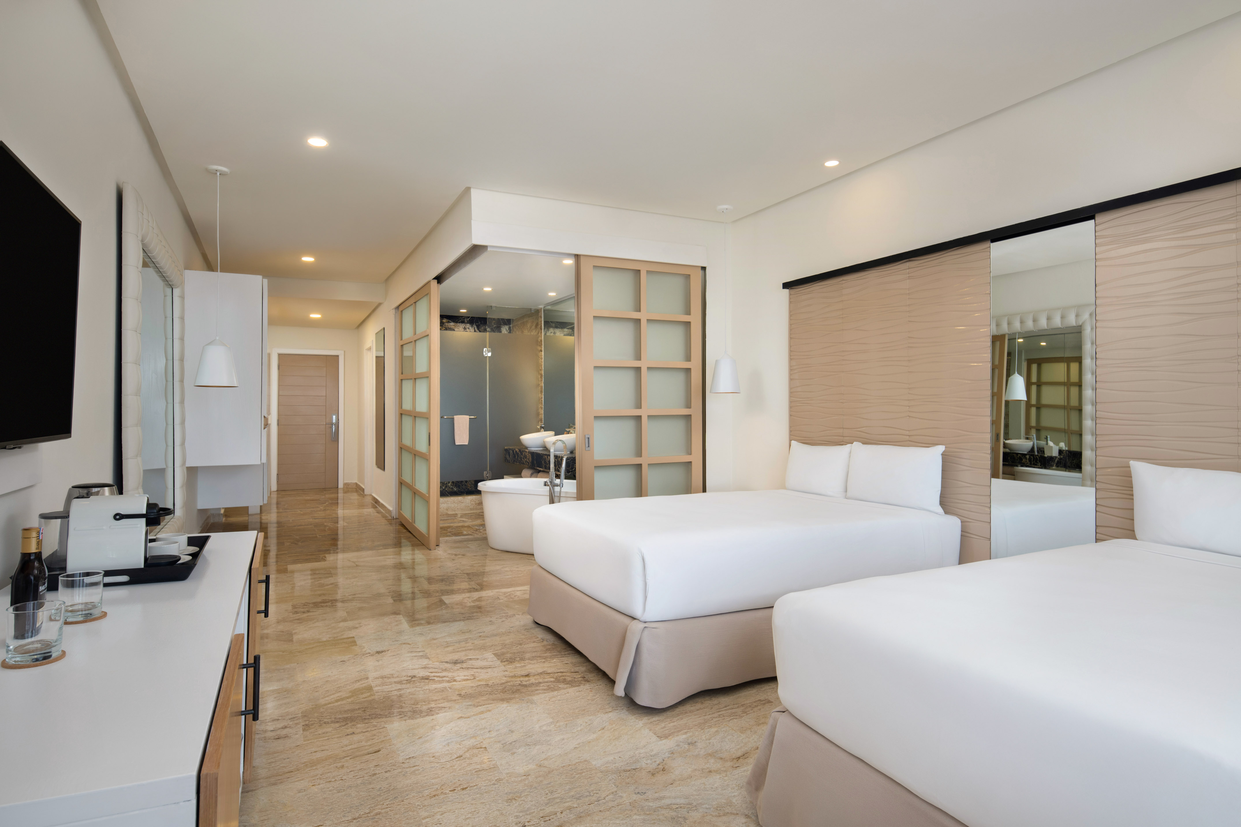 Modern hotel room with two beds, marble floor, and en-suite bathroom.