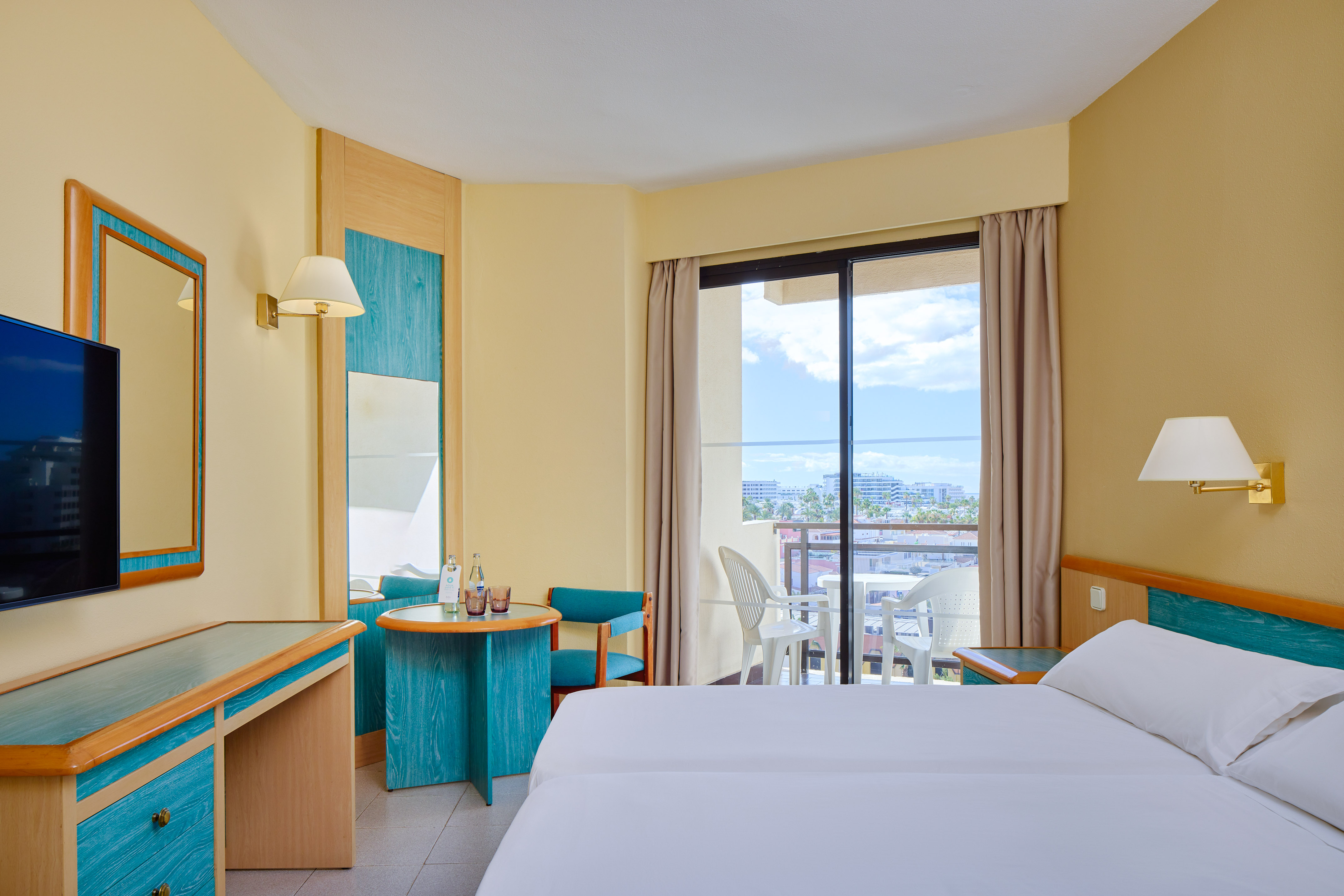 a room with two beds and a table and chairs