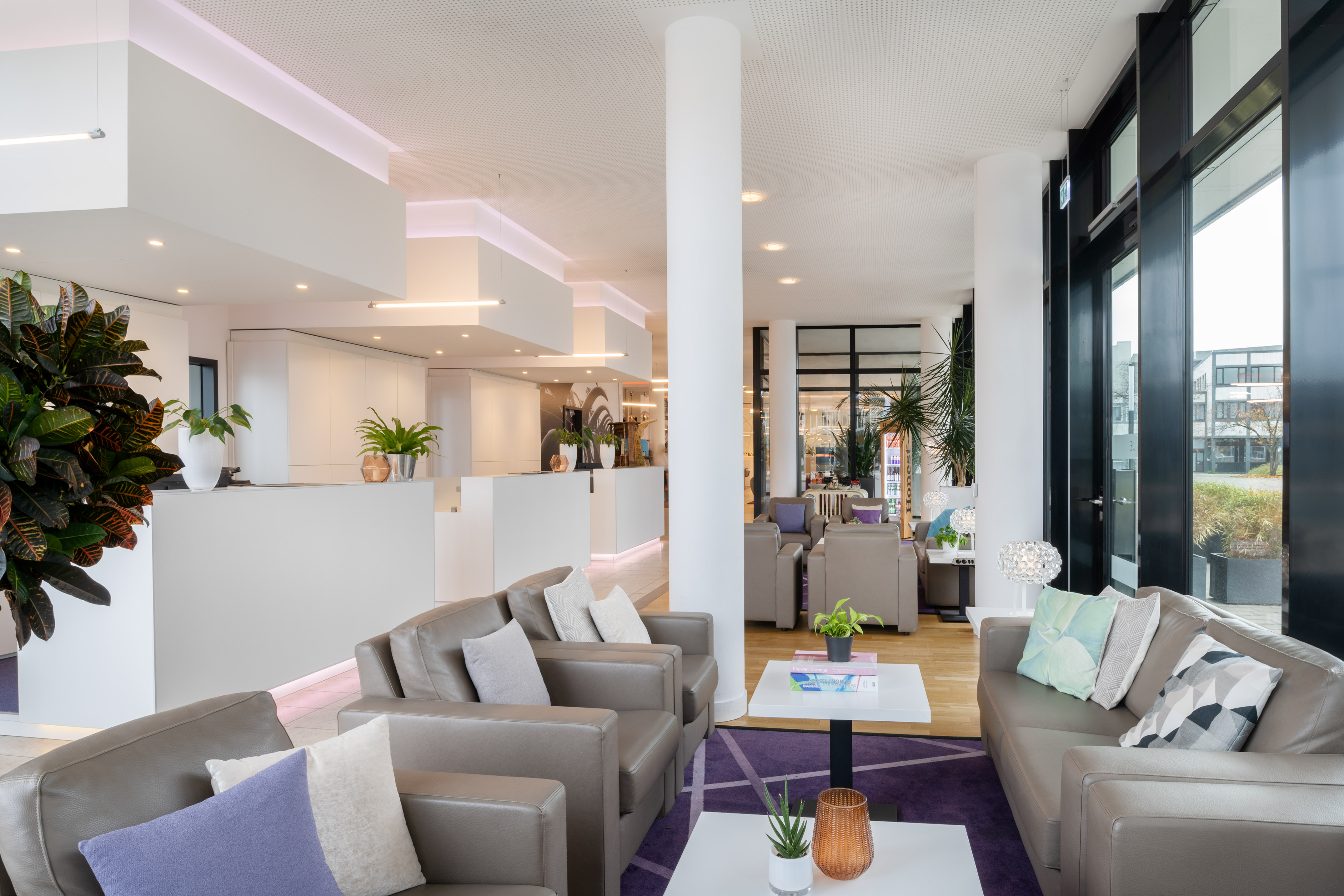 Modern hotel lobby with comfortable leather seating and white reception area.