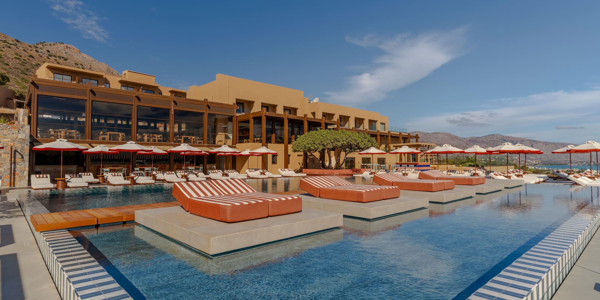 a pool with lounge chairs and umbrellas in front of a building