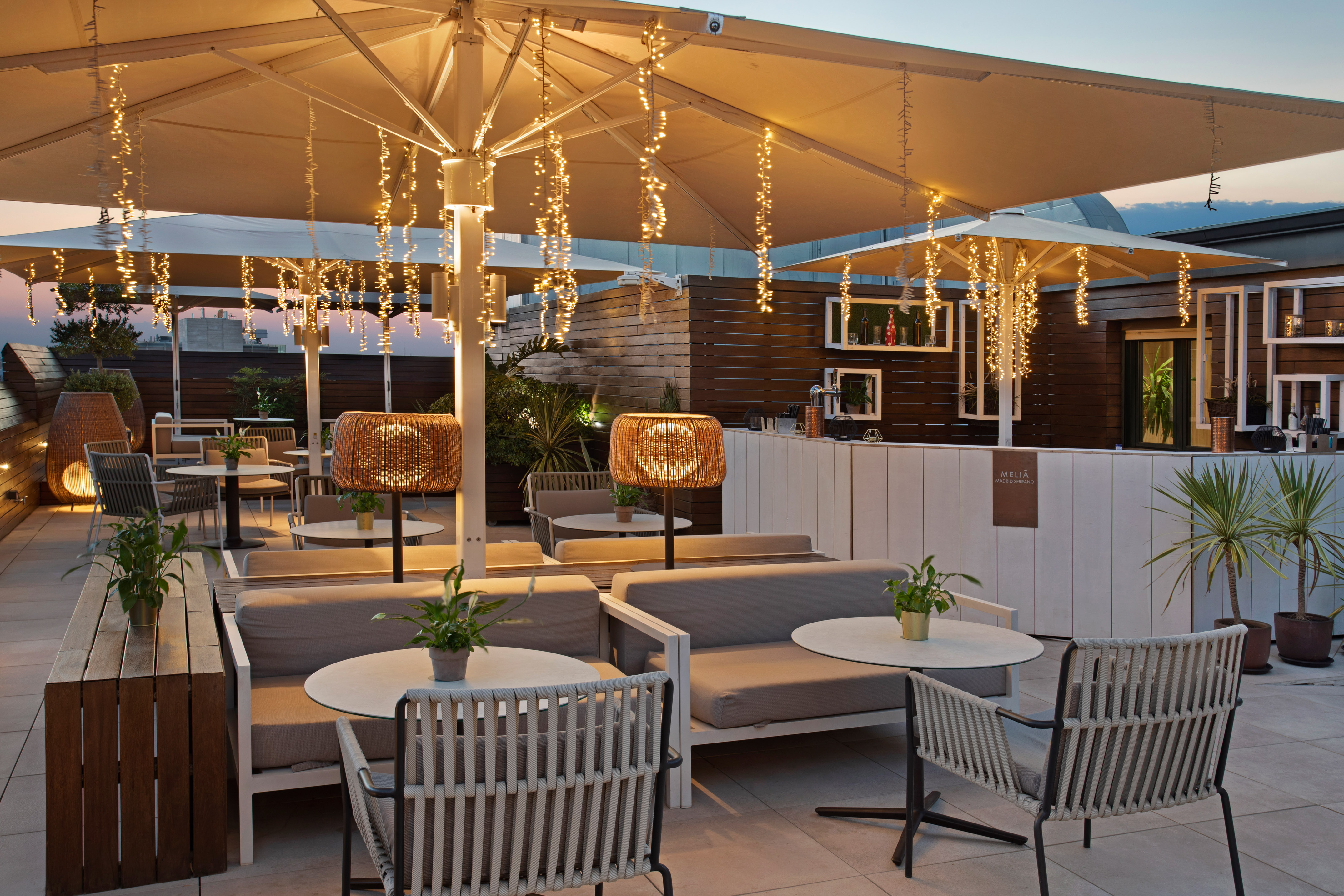 Hotel rooftop lounge at dusk with ambient string lights and modern patio seating.