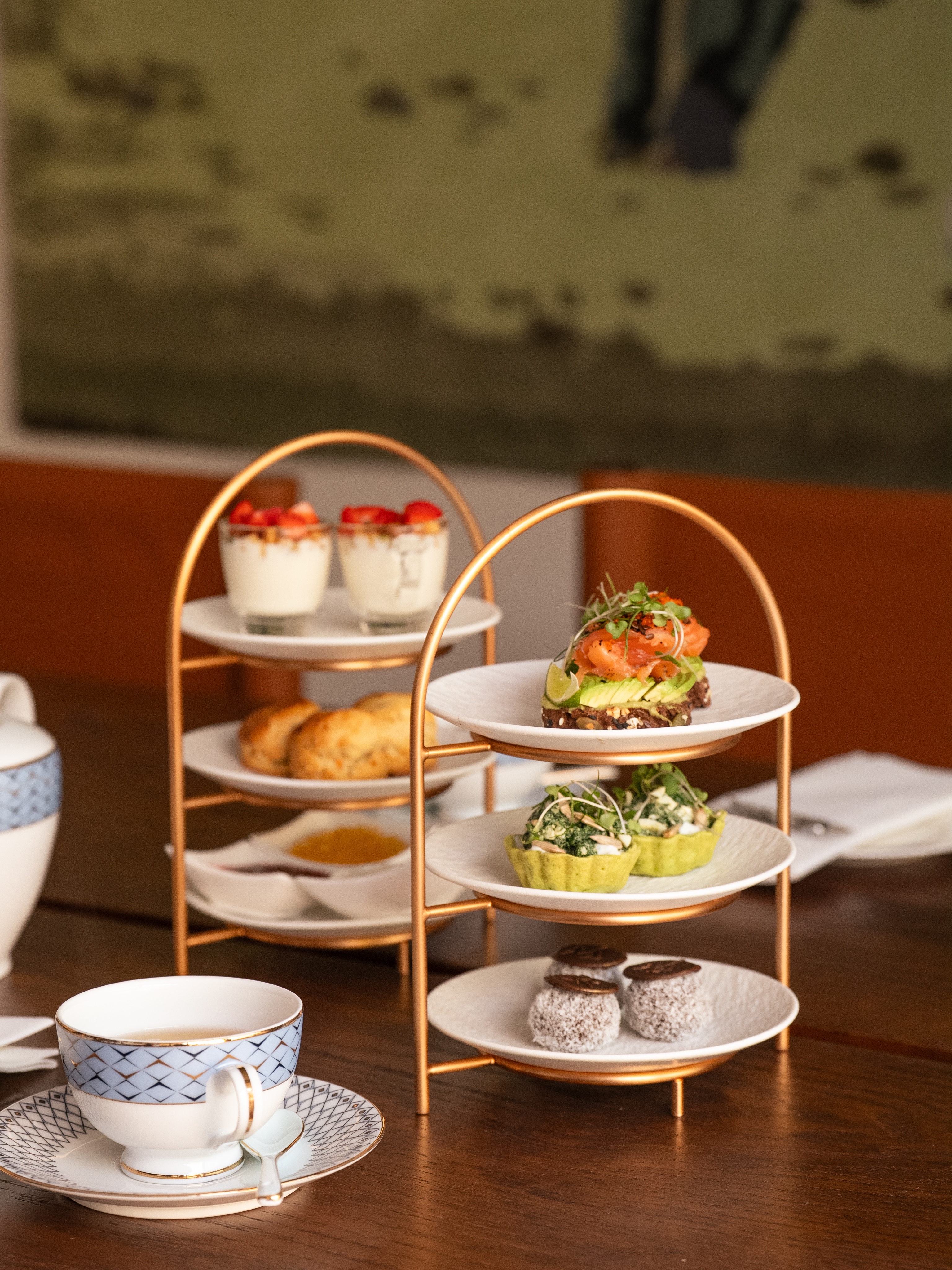 Golden tiered stands of afternoon tea sandwiches, scones, sweet pastries, and tea.
