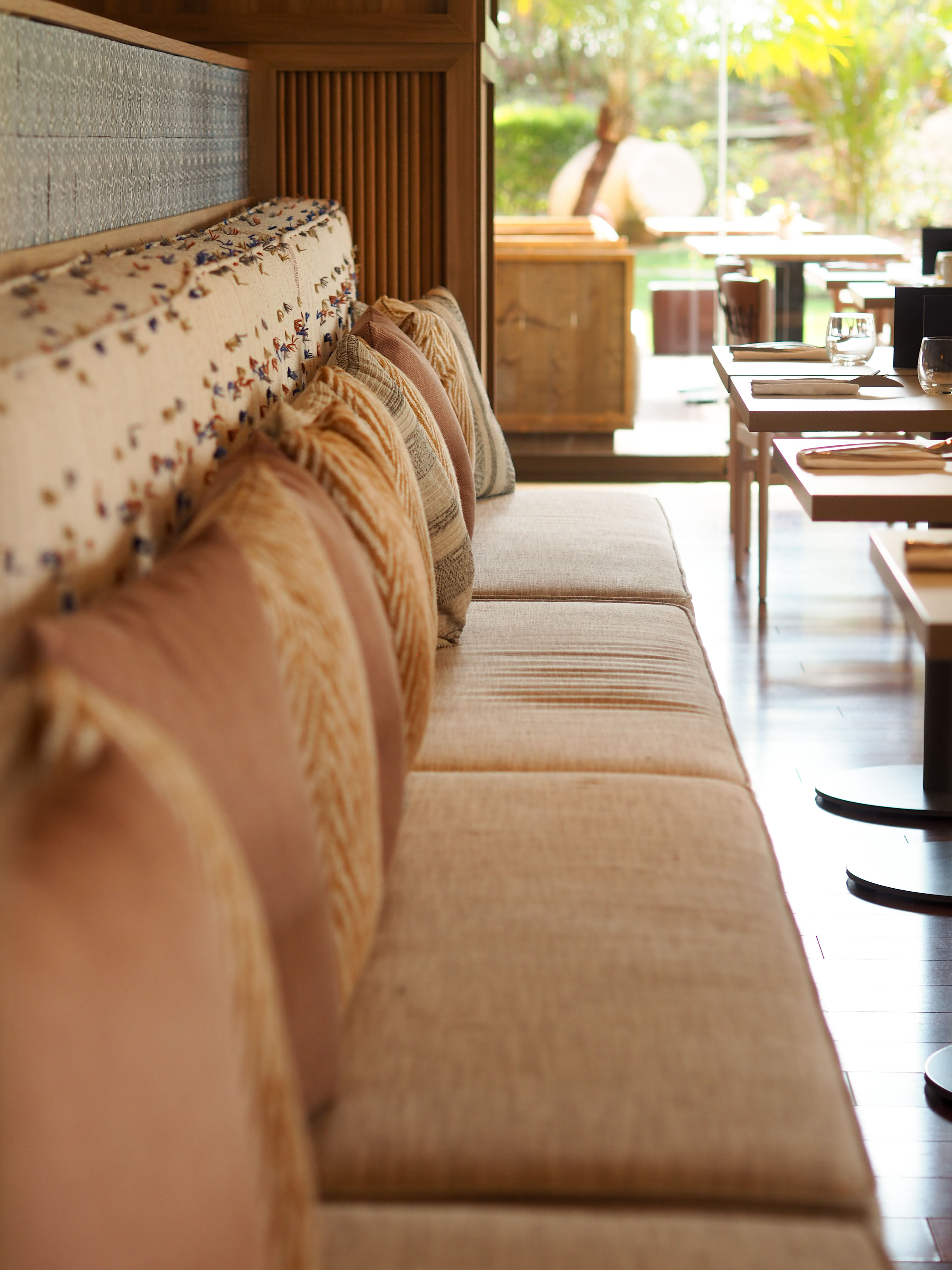 Restaurant booth seating, patterned pillows, bright dining area, garden view.