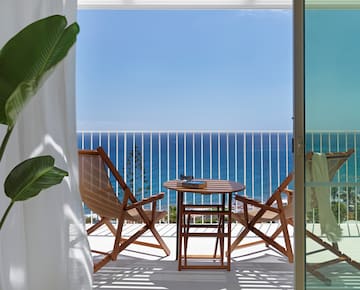a deck with chairs and a table overlooking the ocean