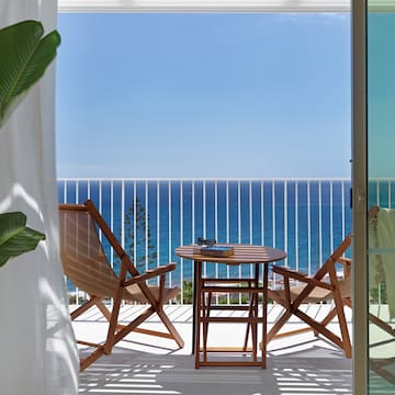 a deck with chairs and a table overlooking the ocean