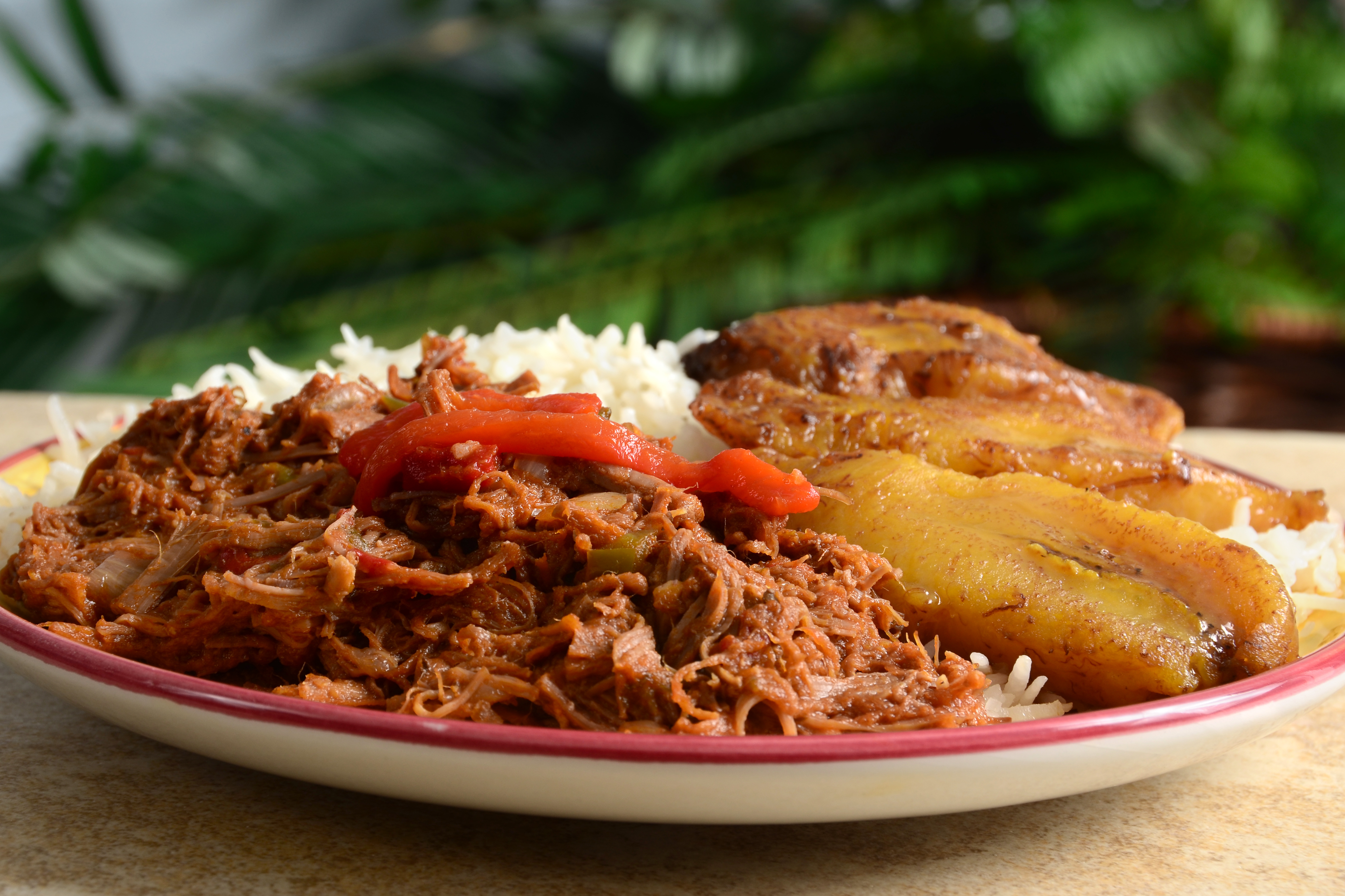 Ropa Vieja con arroz blanco, plátano maduro frito y pimientos rojos.