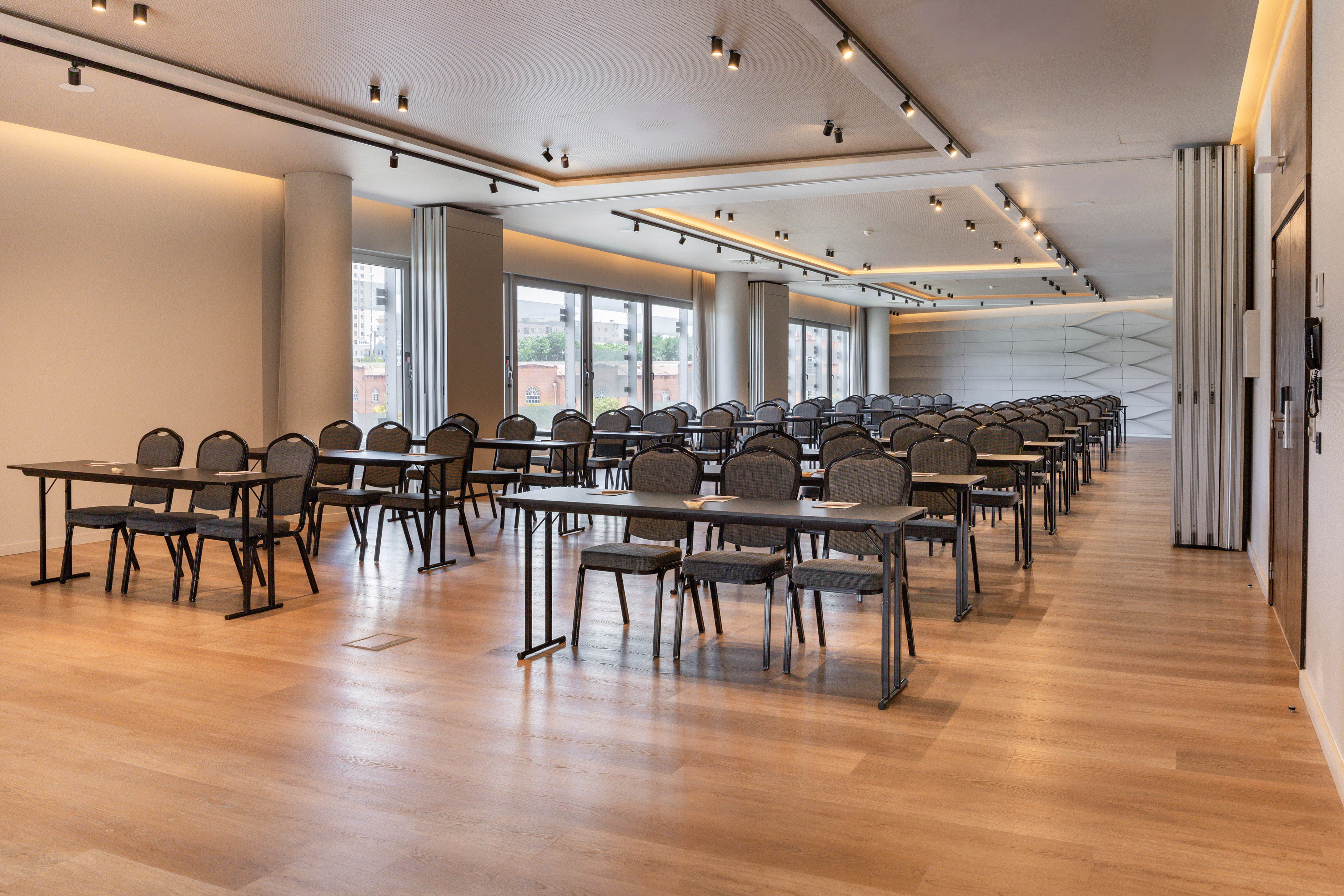 Modern empty conference room with rows of tables, chairs, and large windows.