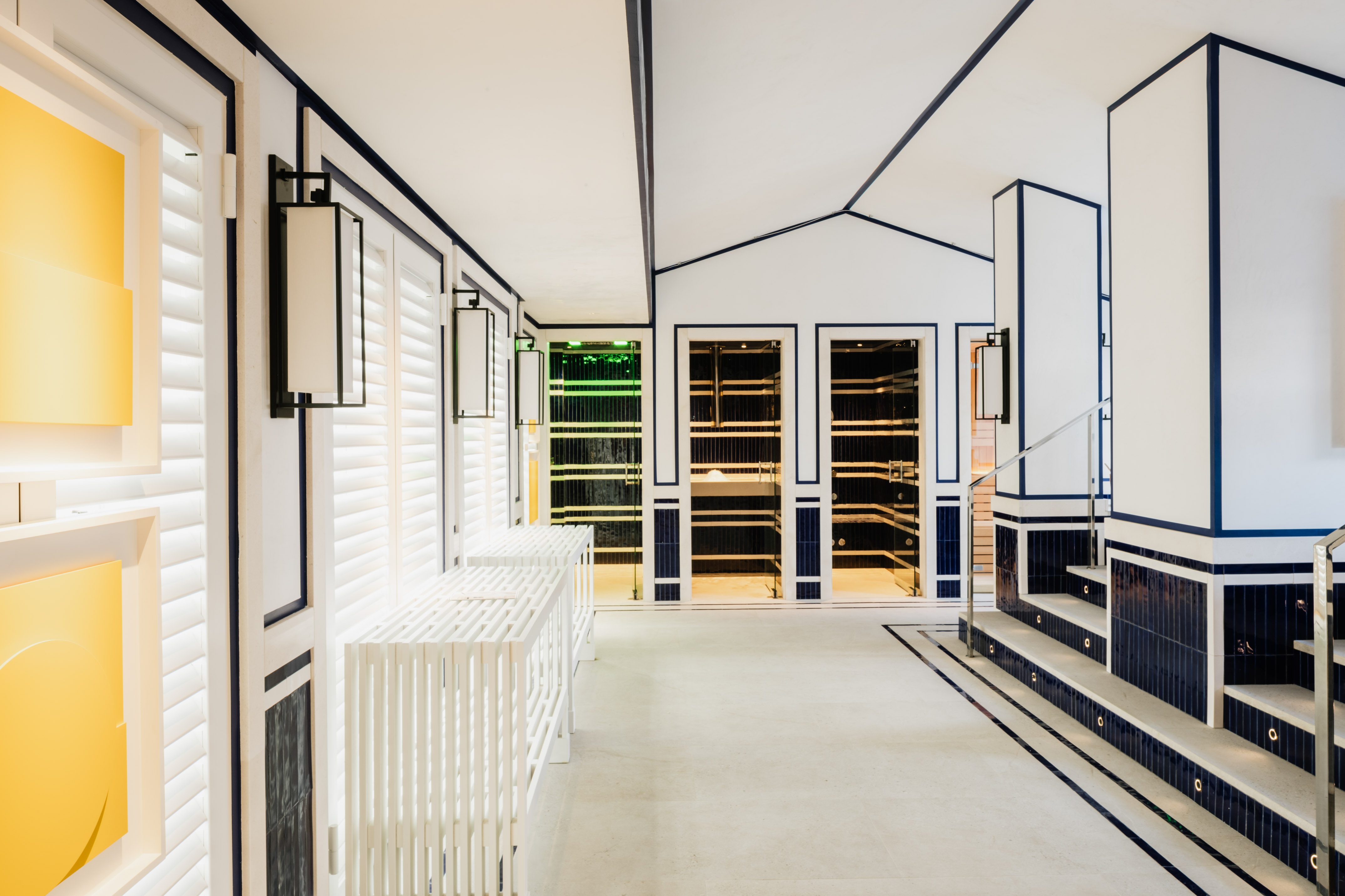 Minimalist white interior with bold navy accents, sauna rooms, and stairs.