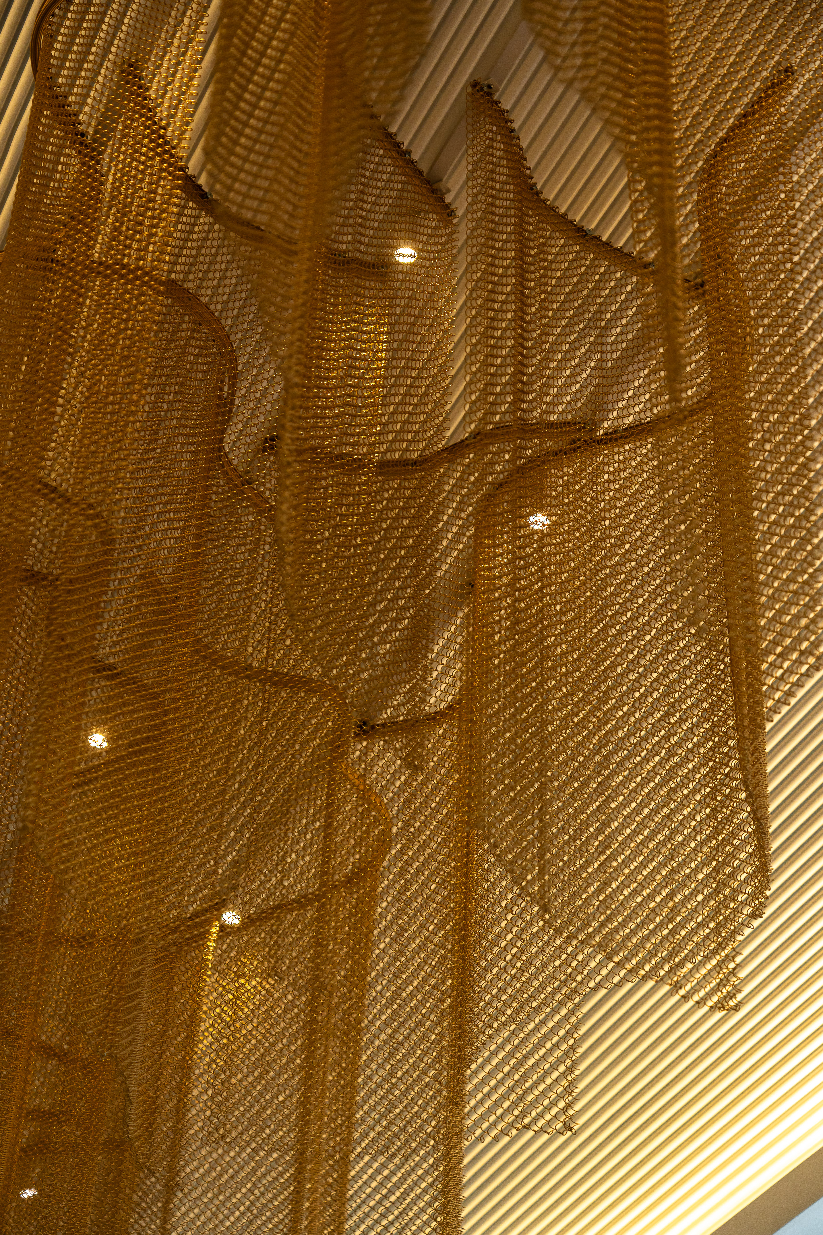 Golden metallic mesh ceiling decor with recessed lighting.