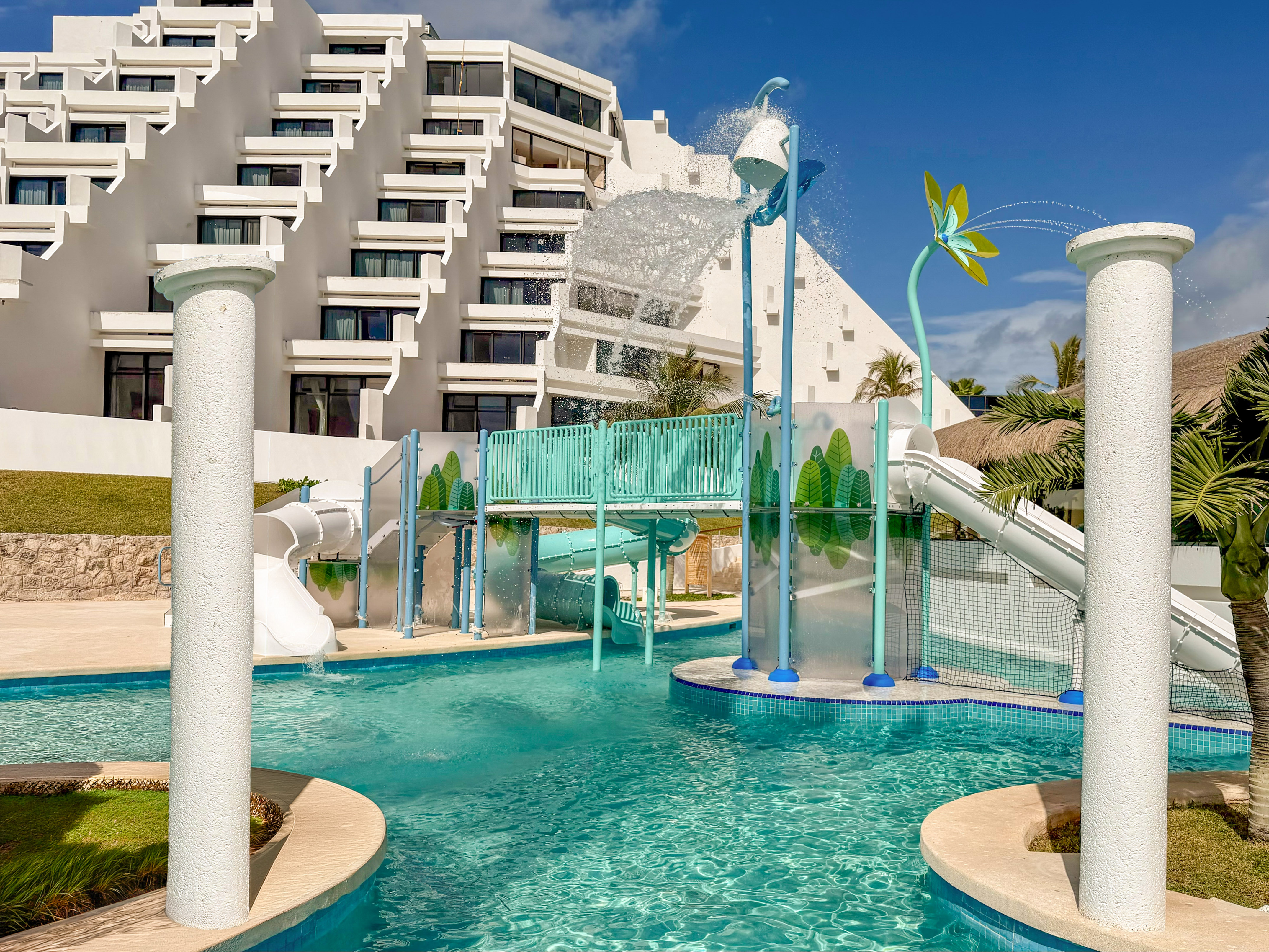 Family resort water park with slides, splash bucket, and tiered hotel.