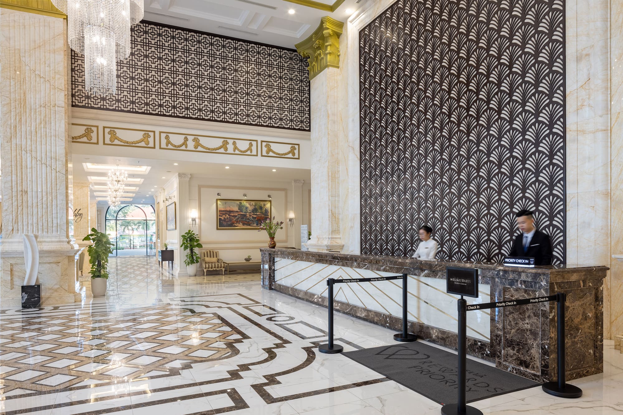 Luxurious Meliá hotel lobby, marble reception desk, intricate floor, staff.