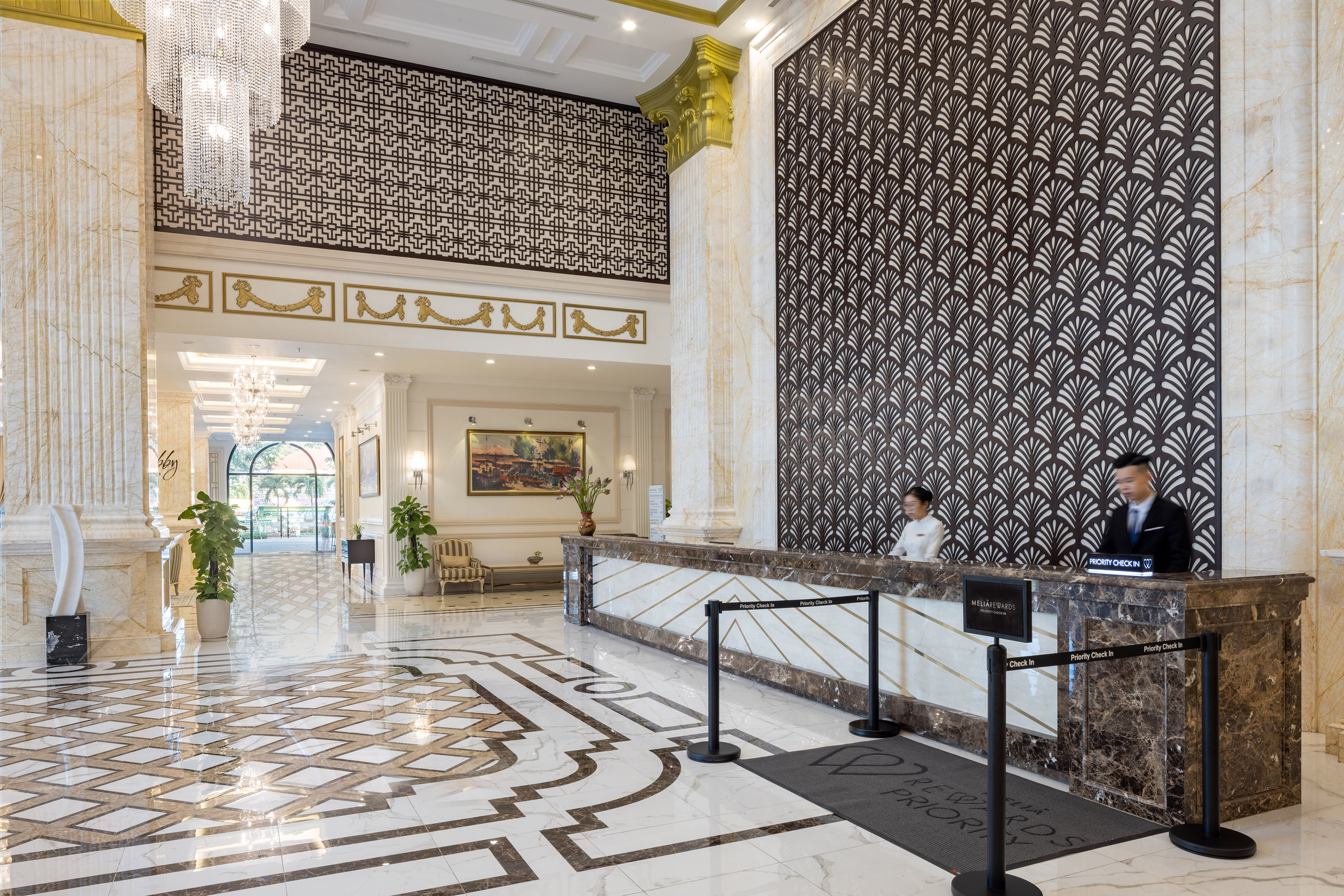 Luxurious Meliá hotel lobby, marble reception desk, intricate floor, staff.