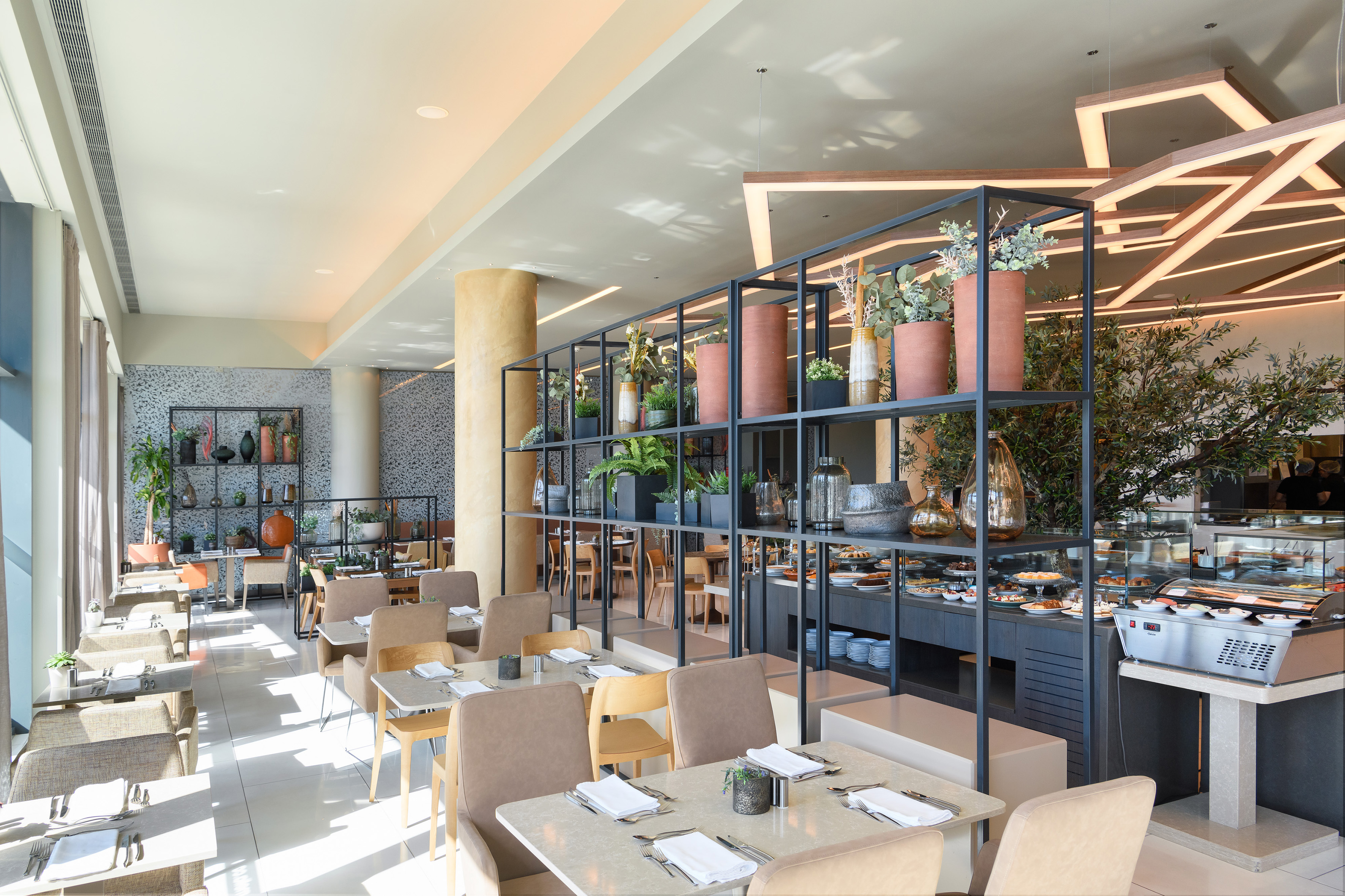 Contemporary restaurant interior with tables, plant decor, and buffet.