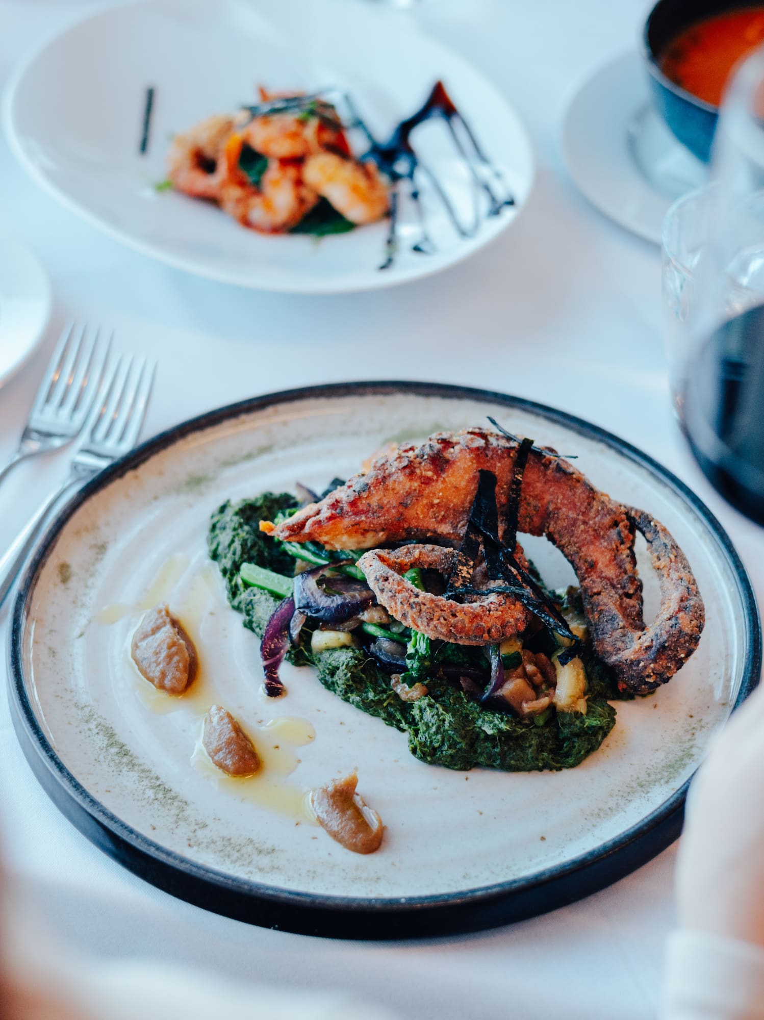 Gourmet fried octopus, vegetables, red wine in a fine dining restaurant.