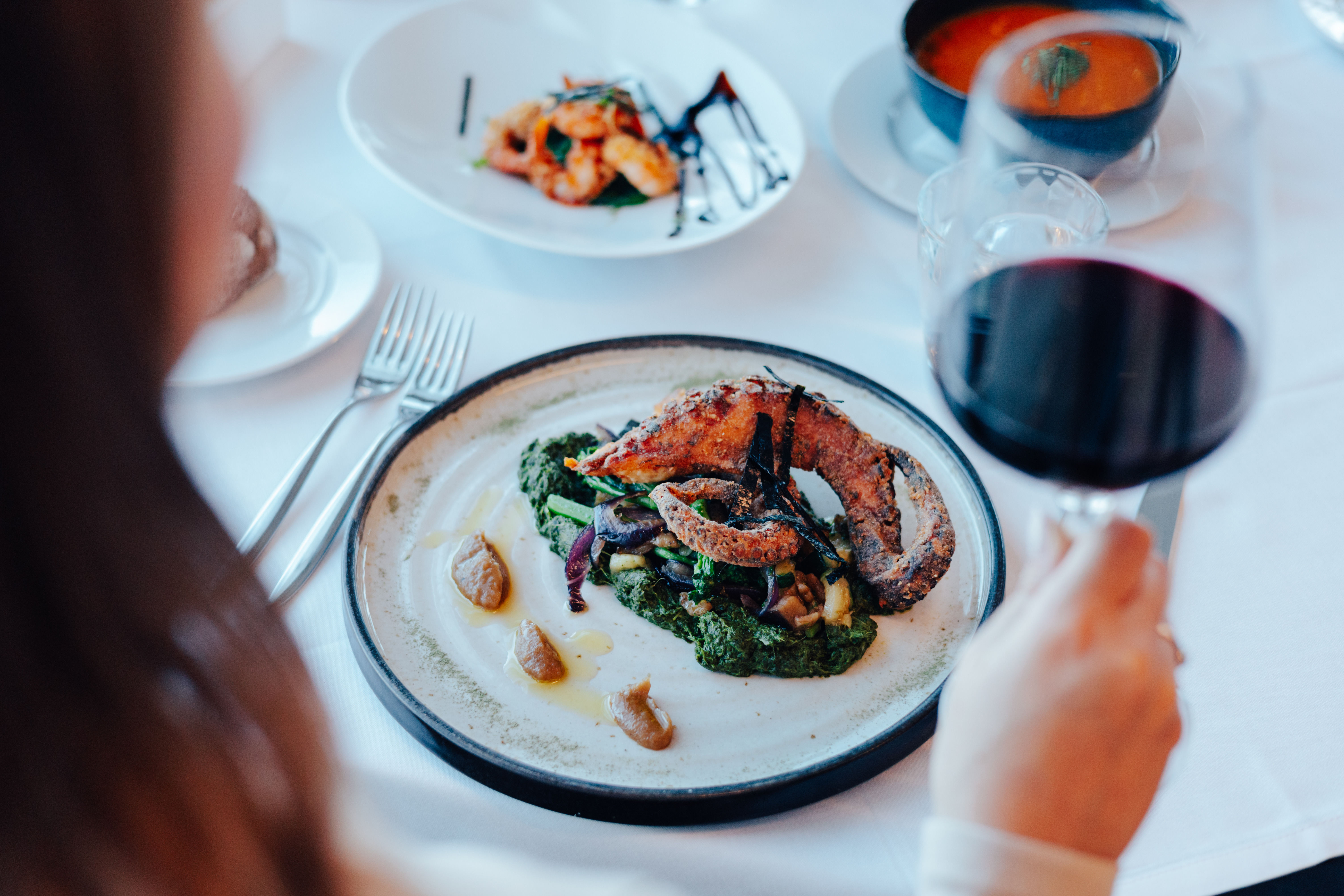 Gourmet fried octopus, vegetables, red wine in a fine dining restaurant.