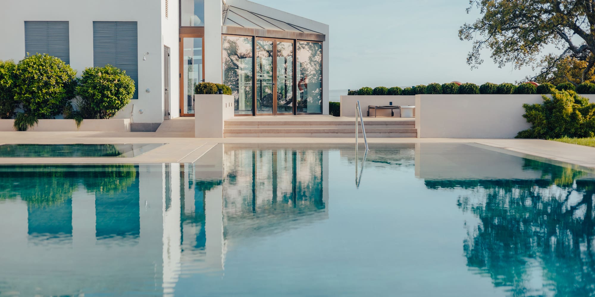 Luxury modern white villa, expansive swimming pool reflecting architecture.