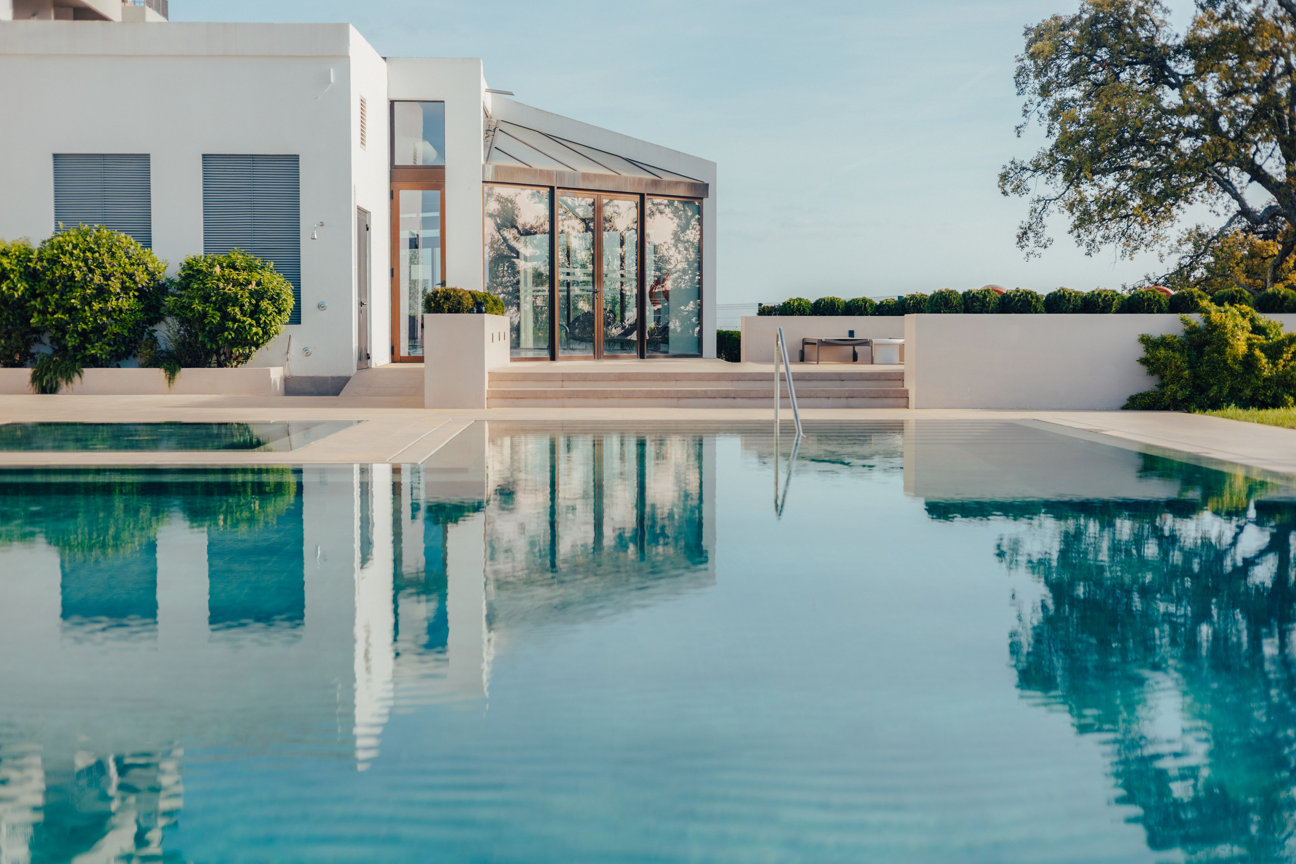 Luxury modern white villa, expansive swimming pool reflecting architecture.
