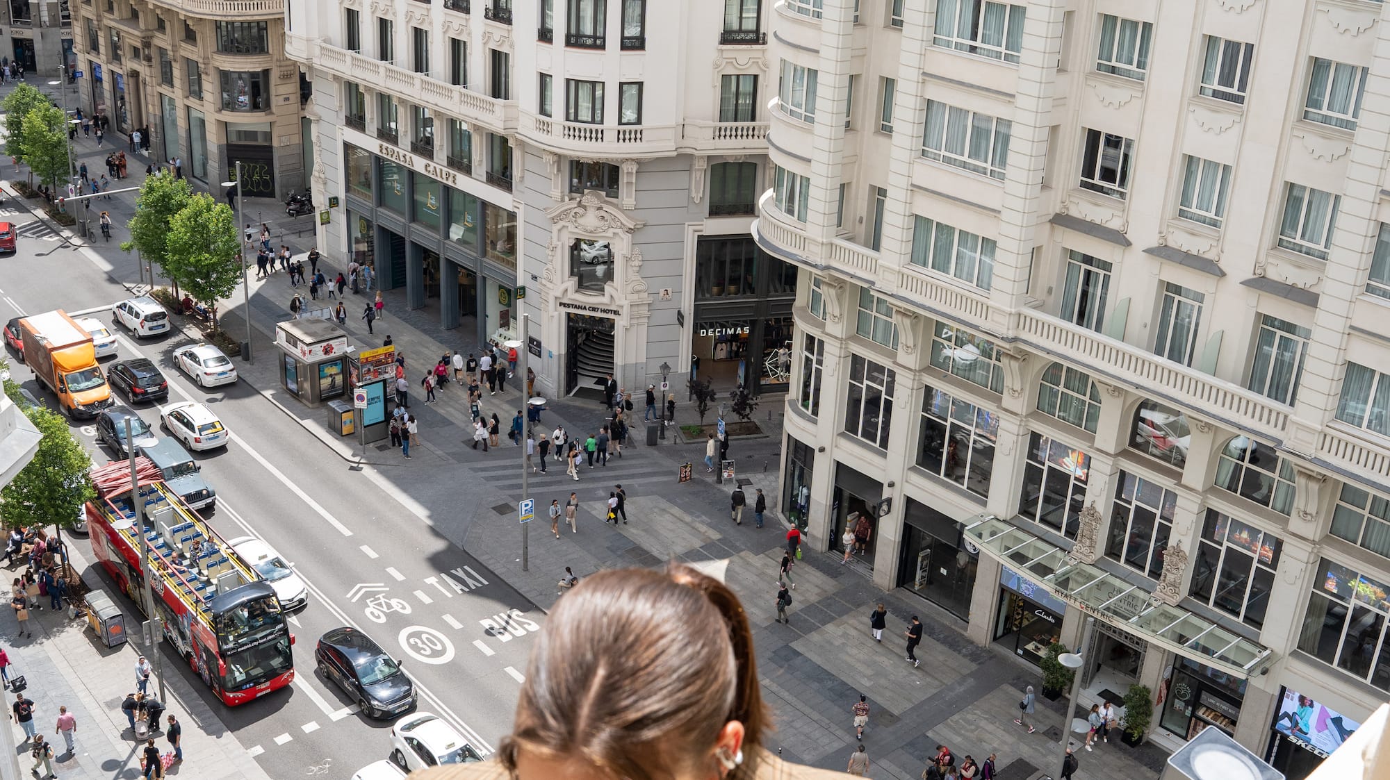 a woman standing on a balcony looking down at a street
