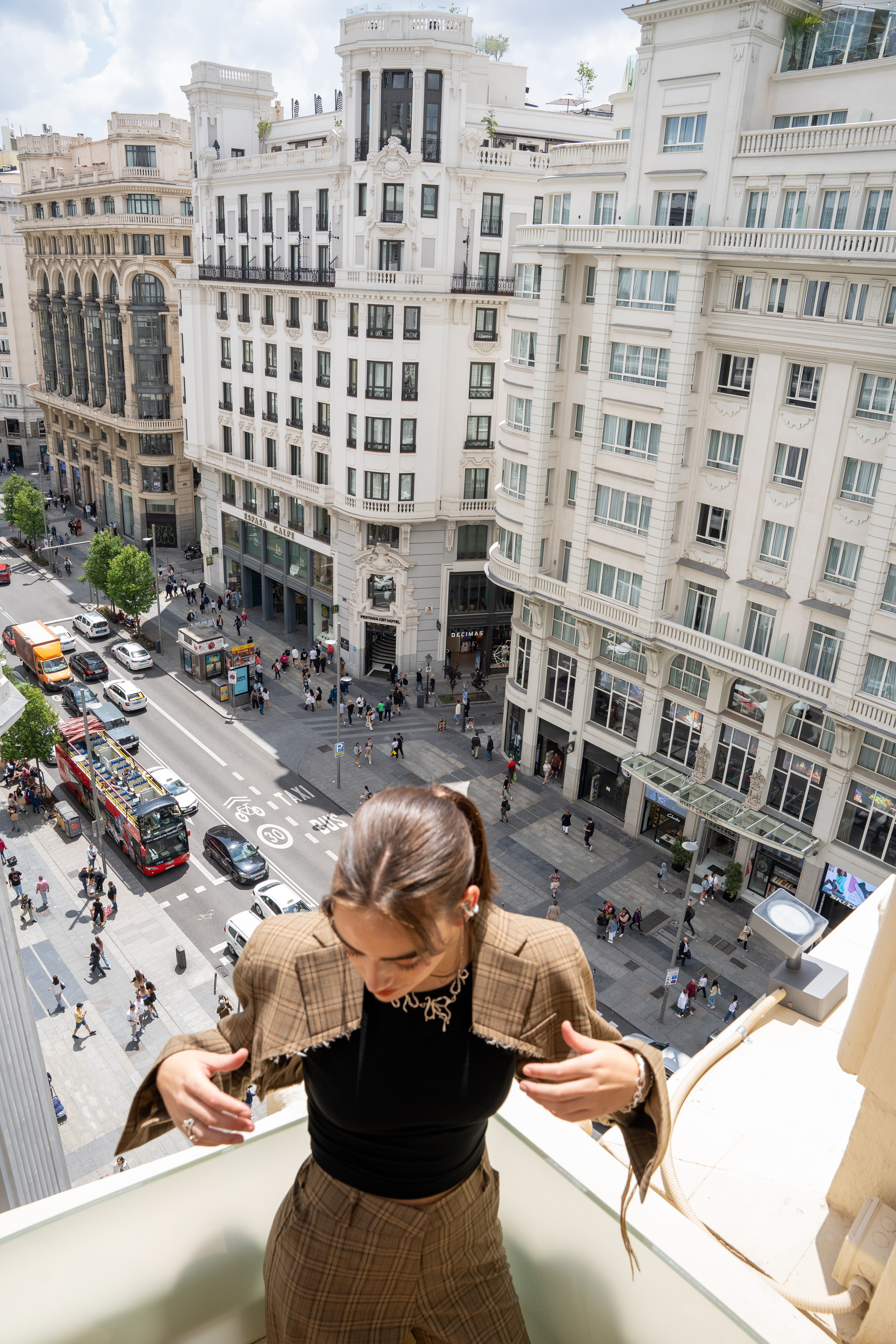 a woman standing on a balcony looking down at a street