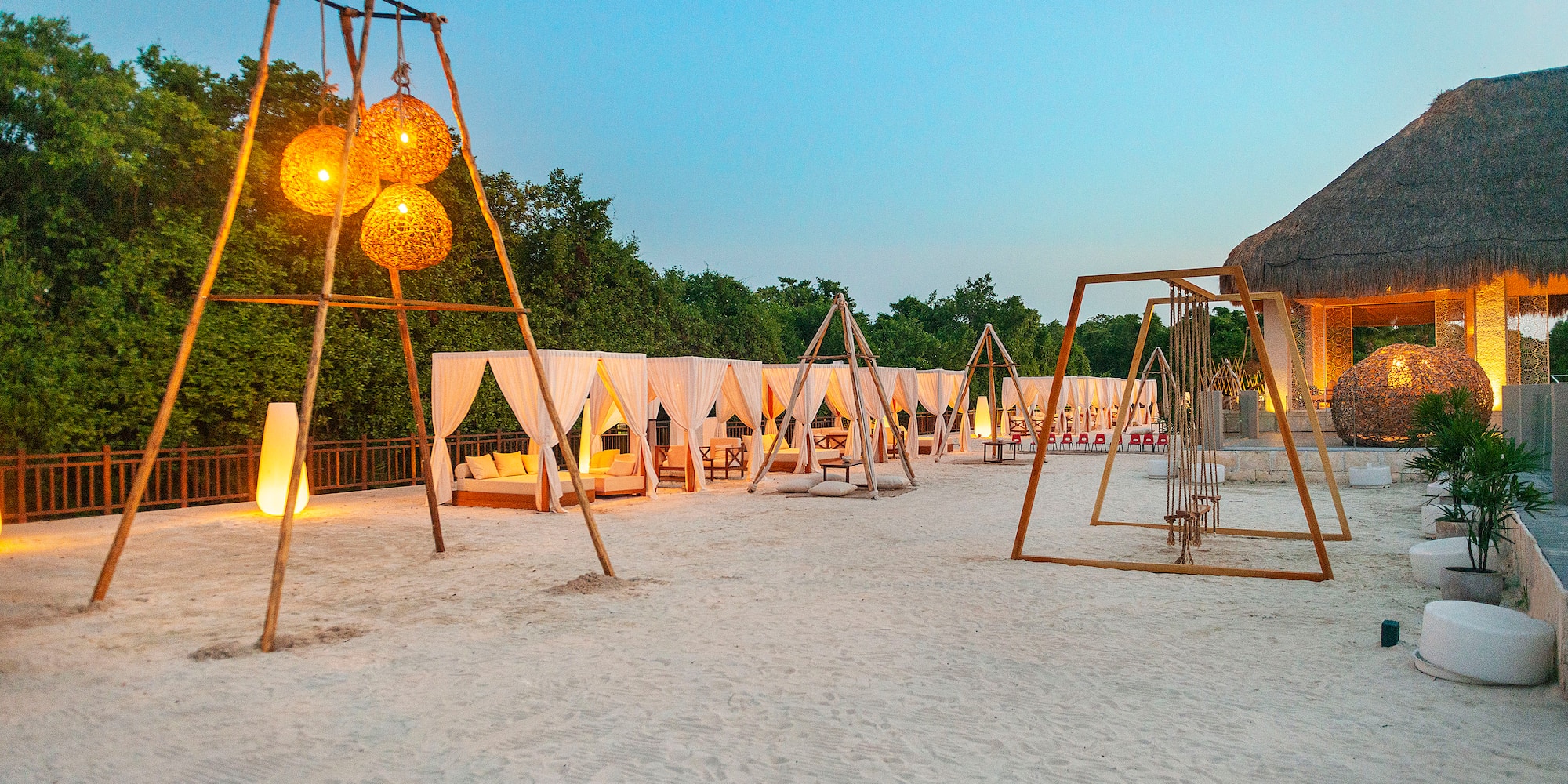 a group of tents and swings in a sandy area