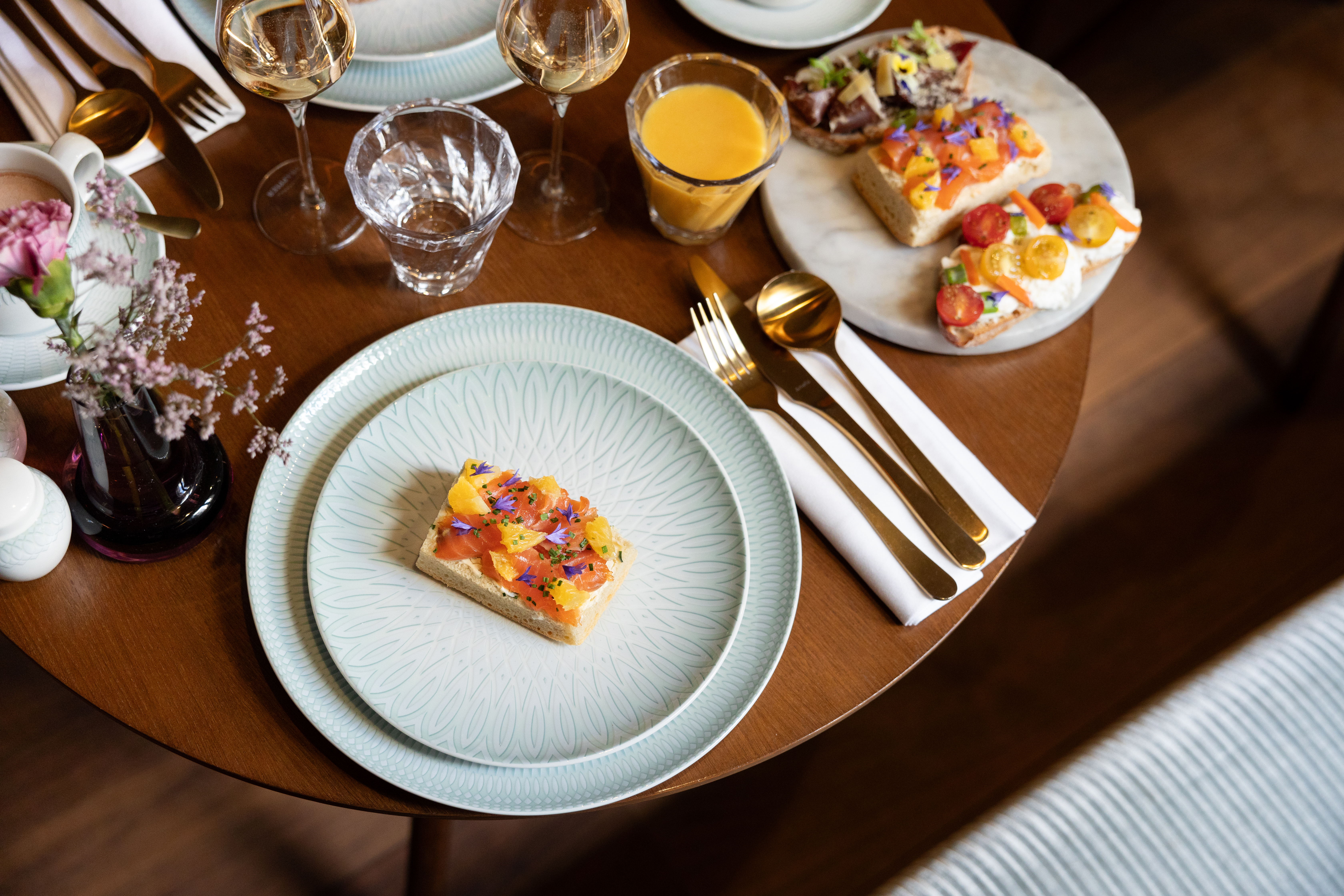Gourmet breakfast: salmon bruschetta, colorful toasts, wine, juice on wooden table.