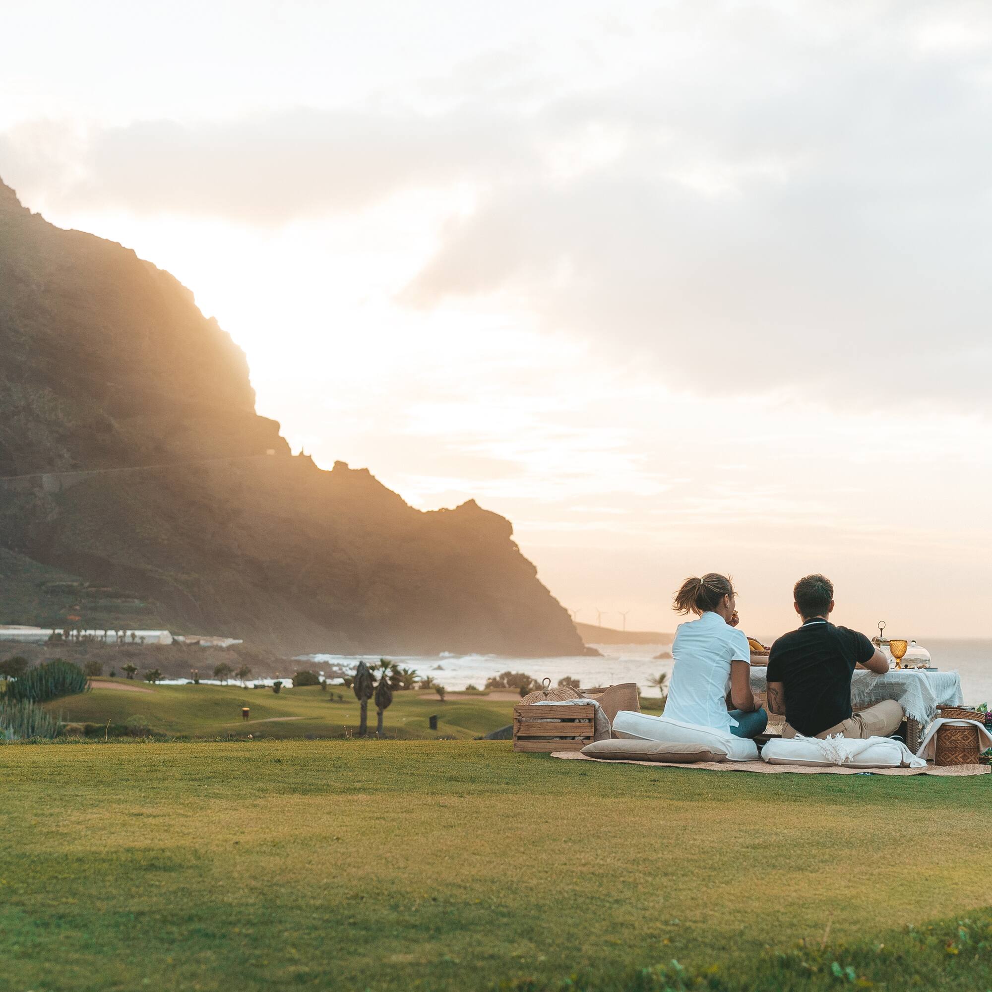 a group of people sitting on a blanket on a grassy field