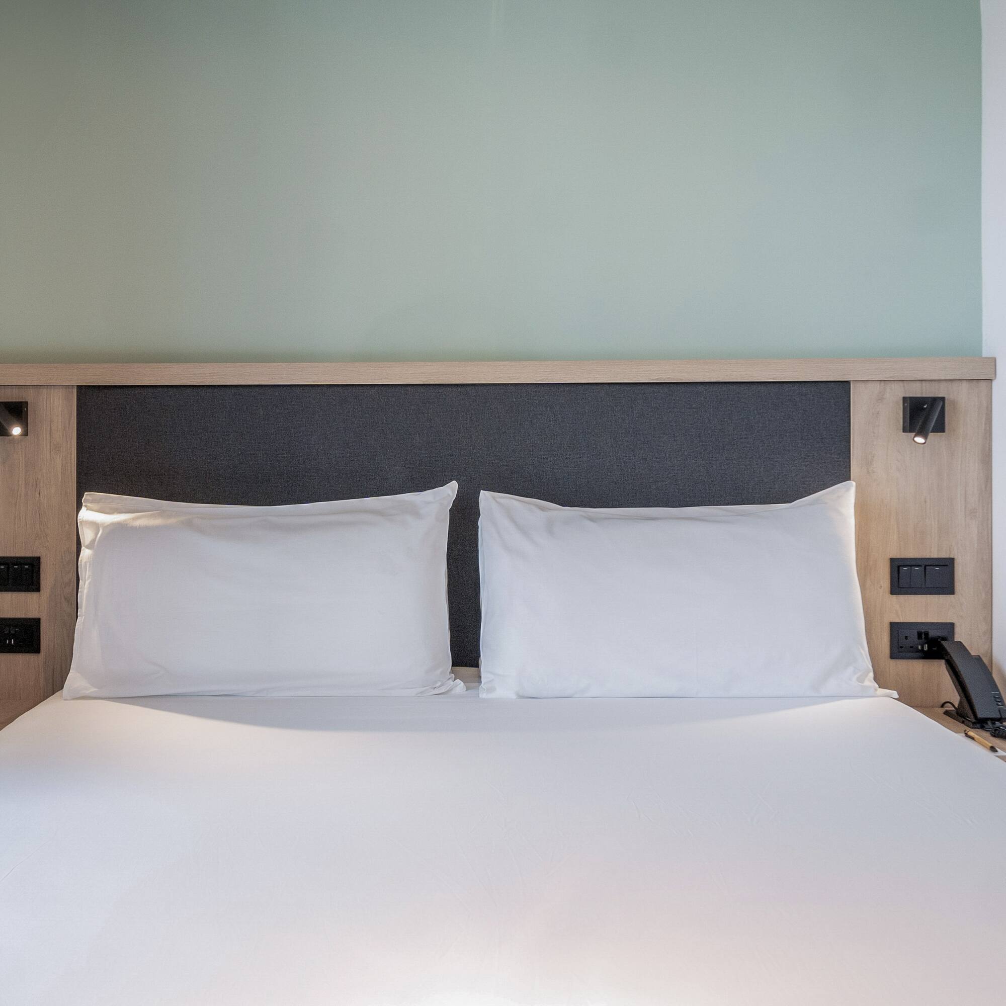 a bed with white sheets and a wooden headboard