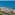 Coastal resort with pools, palm trees, and lighthouse overlooking blue ocean.