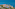 Coastal resort with pools, palm trees, and a lighthouse by the blue ocean.