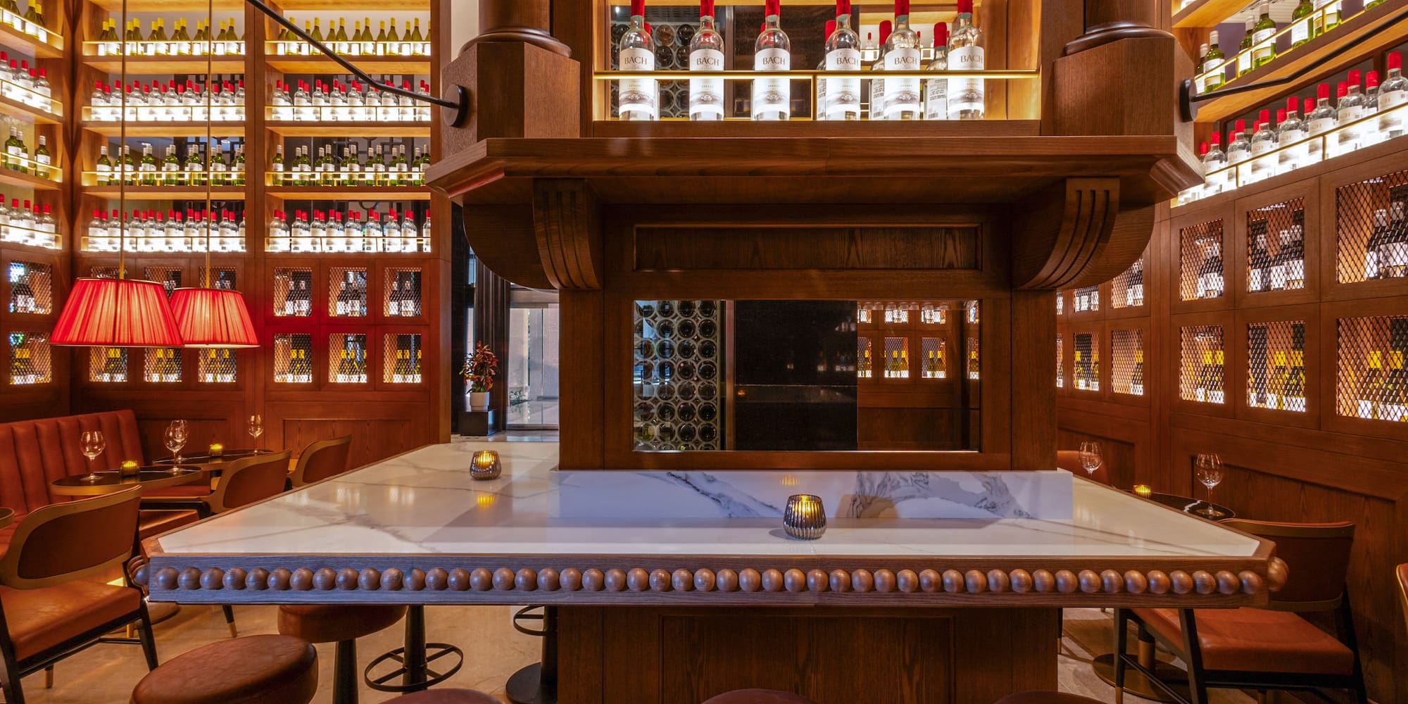 Elegant bar with wooden wine bottle displays, marble counter, and leather stools.
