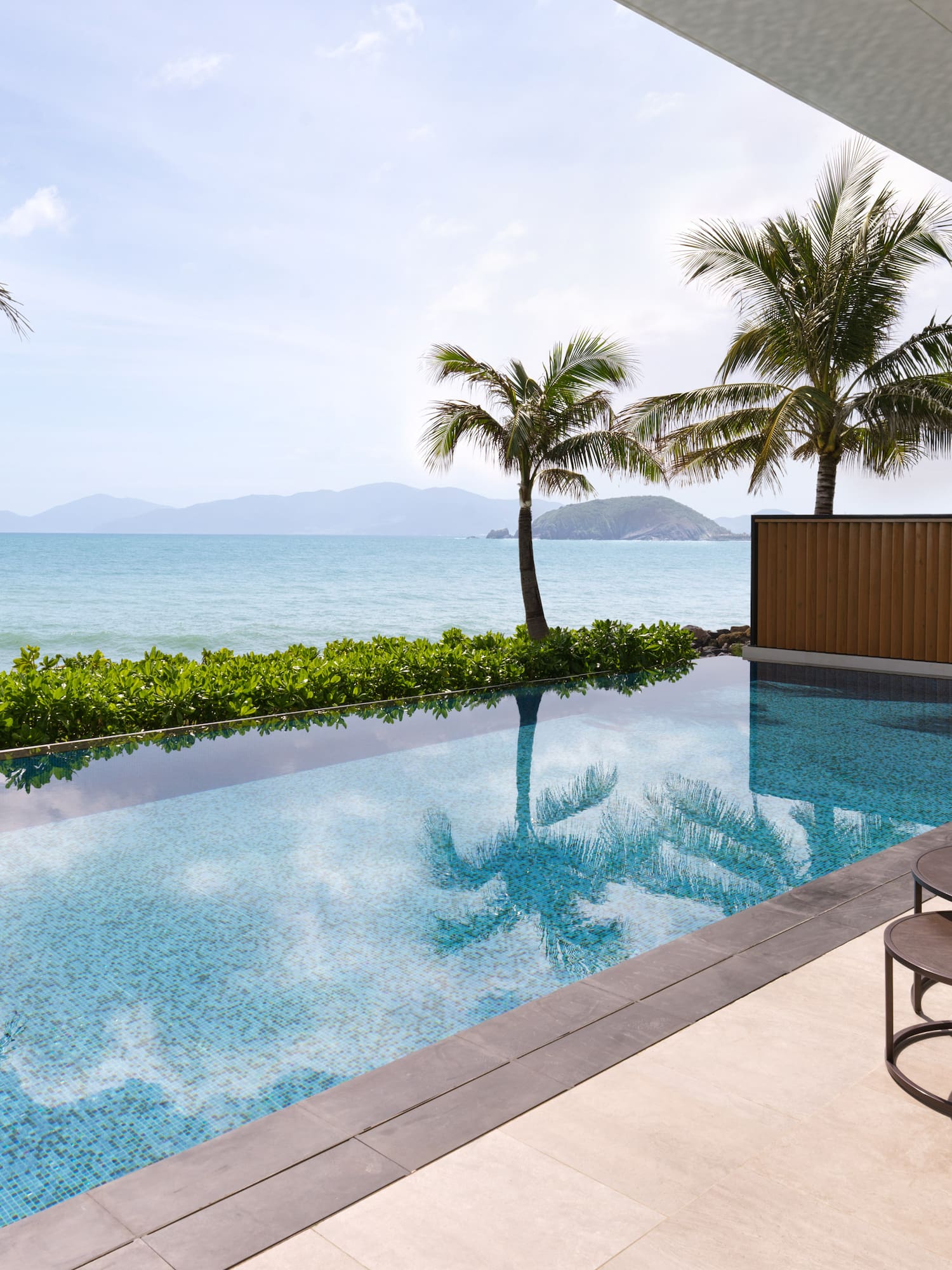 Tropical ocean view infinity pool, luxury resort with palm trees and terrace.