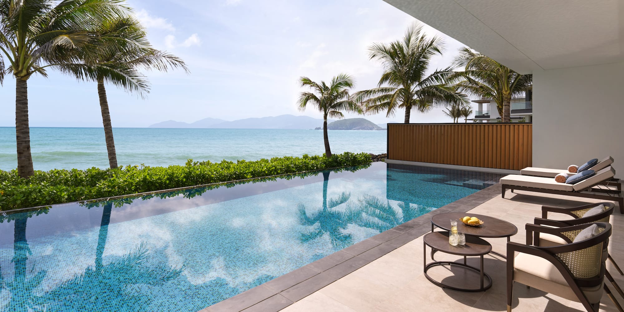 a pool with a table and chairs by a house with a body of water